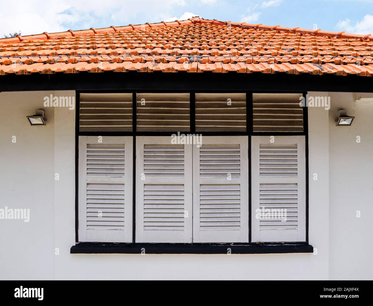 Nahaufnahme der Antike hölzerne Fensterläden und roten Ziegeldach einer weiß getünchten im Alter von alten British Colonial bungalow Haus in Singapur Stockfoto