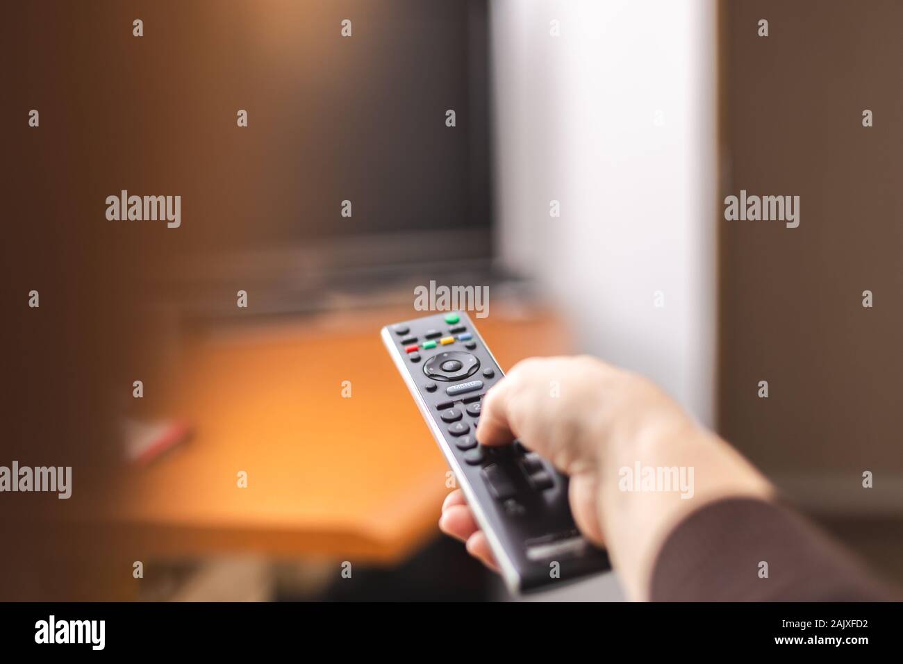 Hand zeigen einer TV-Fernbedienung auf den Fernseher. Zeit, um fernzusehen. Die Fernbedienung in der Hand. Für text Stockfoto