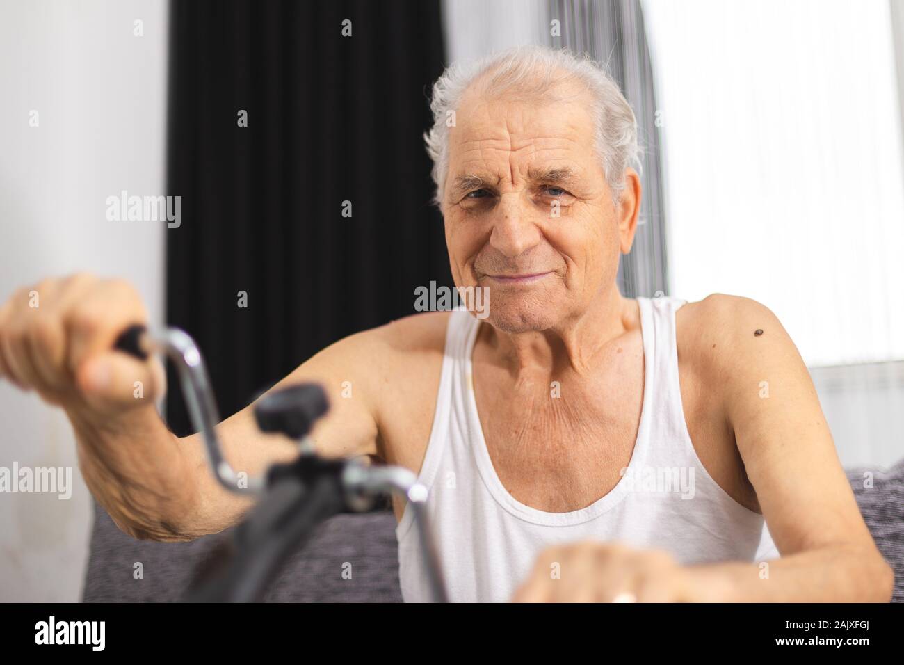 Ältere Menschen stellen Physiotherapie für Gelenke in den Händen an einem Haus für medizinische Geräte Stockfoto