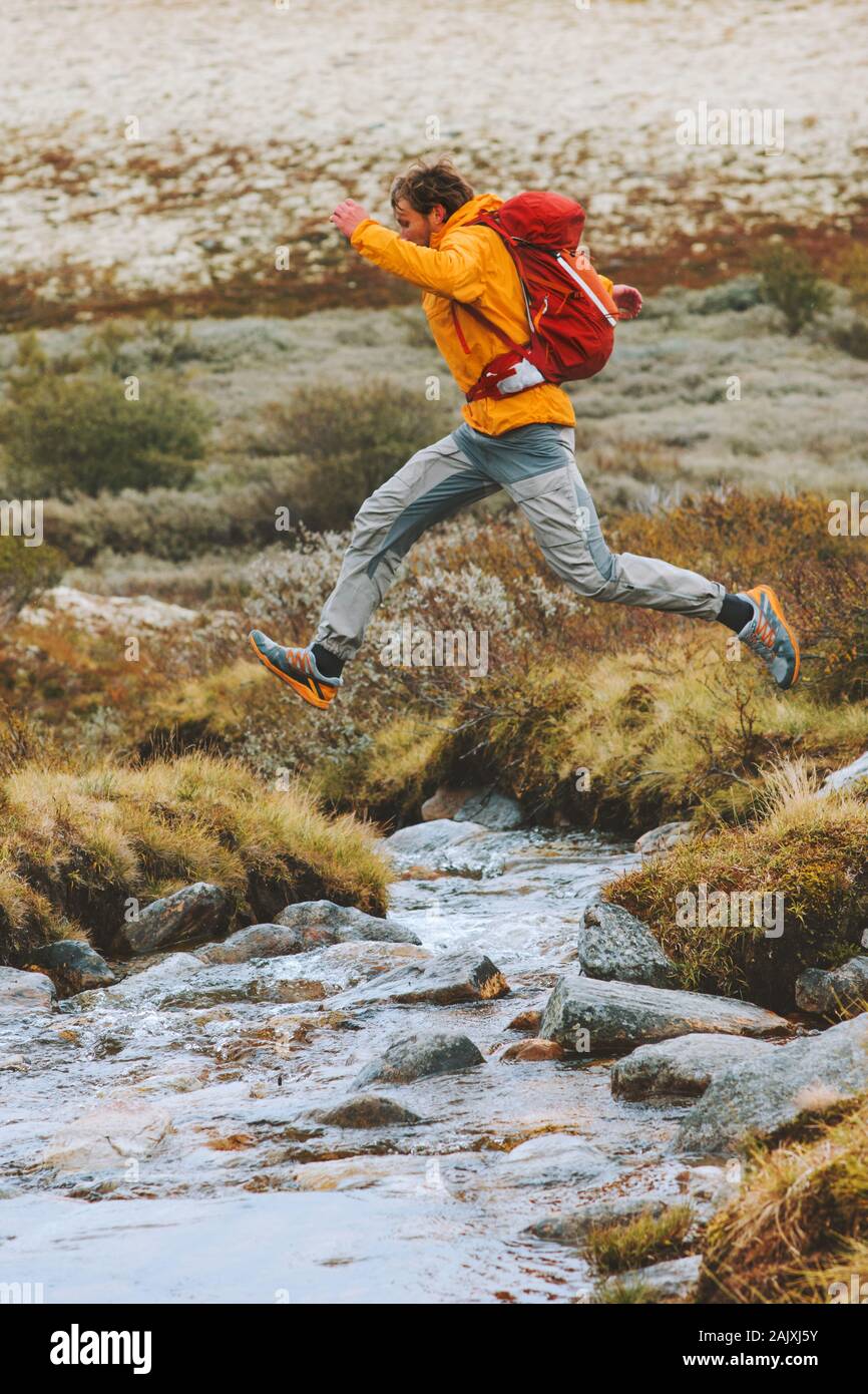 Mann über den Fluss in den Bergen wandern reisen Abenteuer aktiven Lifestyle Urlaub im Freien in Norwegen springen Stockfoto