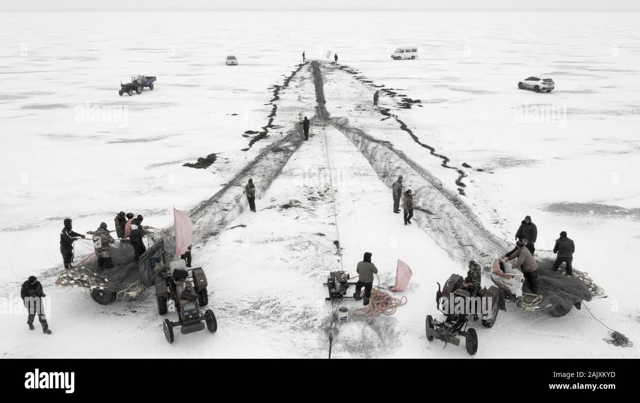 Chinesische Arbeiter ziehen einen riesigen fischernetz Eine gute Ernte auf dem zugefrorenen See in Wolong Kangping County, Shenyang City zu erwarten, im Nordosten Chinas Liaon Stockfoto