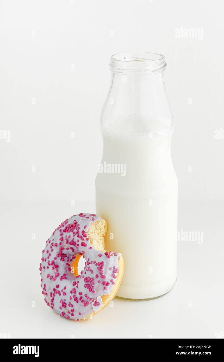 Köstliches Dessert. Flasche Milch und Obst geschmack Donut mit Biss auf weißem Hintergrund. Vertikale. Stockfoto