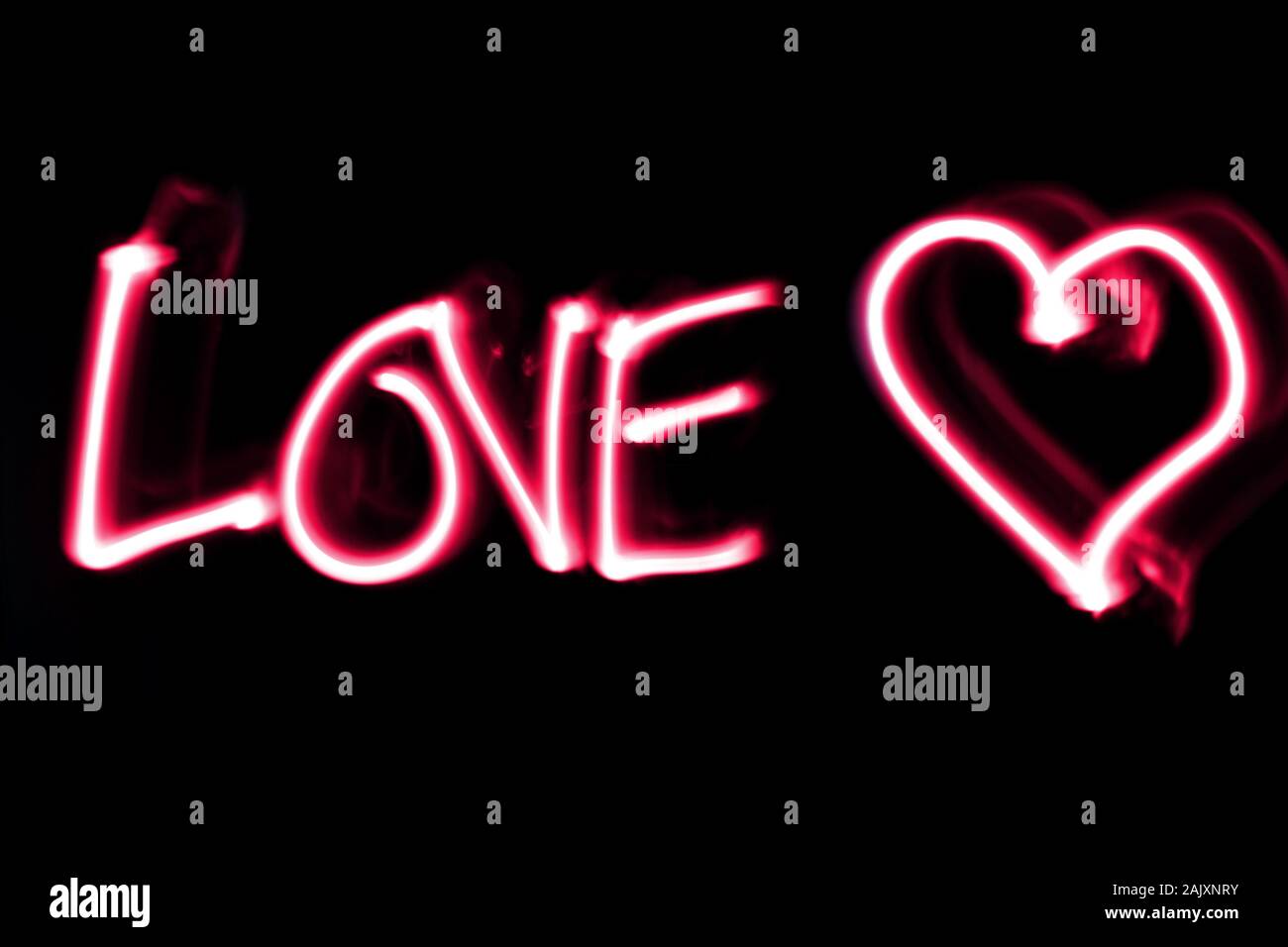 Wort Liebe weiß ein Herz in Pink auf schwarzen Hintergrund. Licht Malerei. Stockfoto