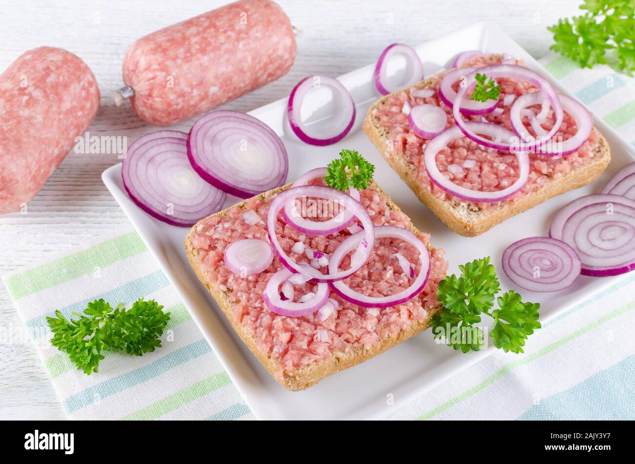 Deutsche Sandwich mit mett Boden Schweinefleisch, Bun- und rohes Fleisch mit Zwiebeln und Petersilie, Nahaufnahme Stockfoto