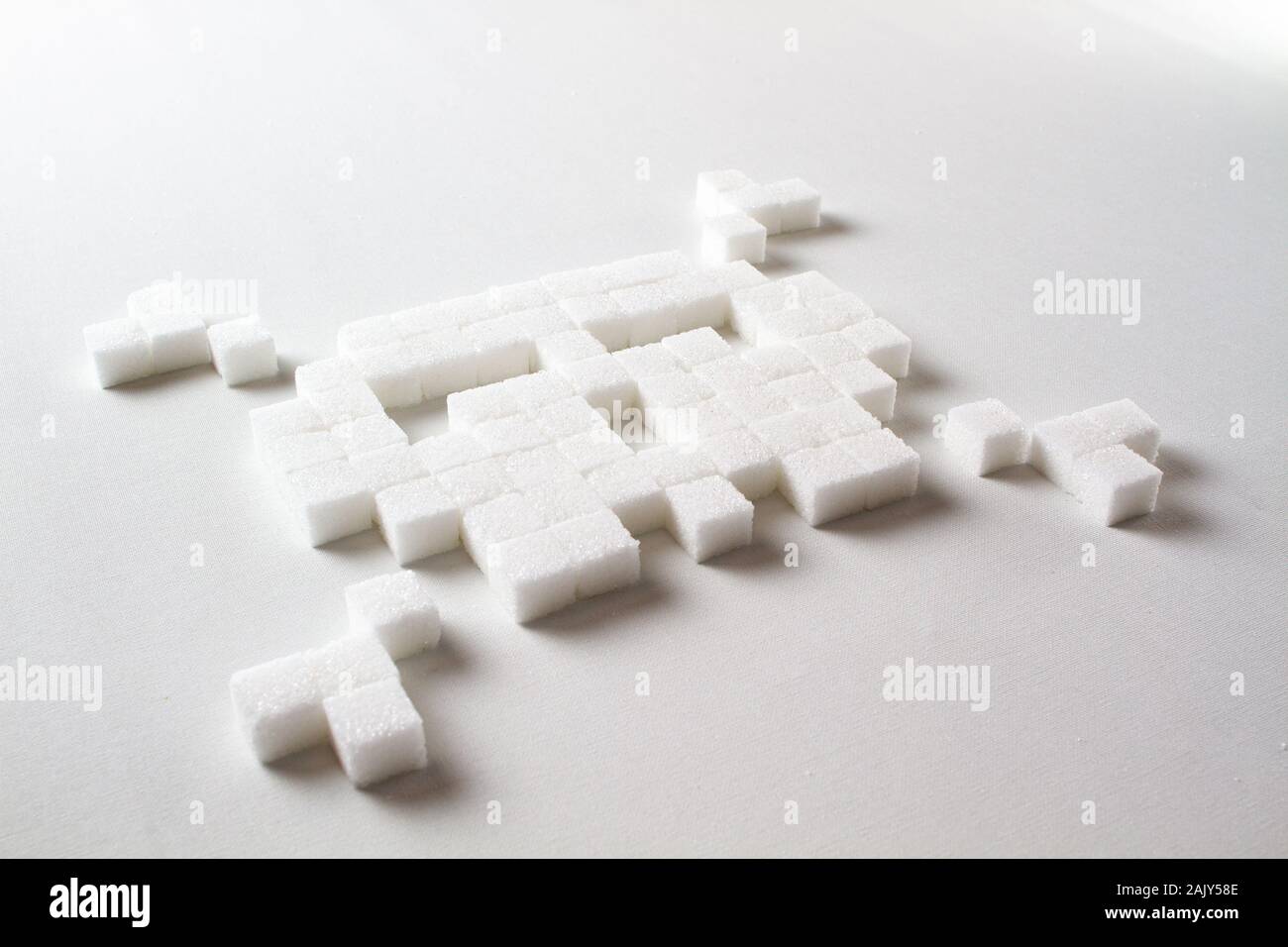 Pixel Art Totenkopf aus Zuckerwürfeln auf weißem Hintergrund symbolisiert ungesunde Nahrung Stockfoto