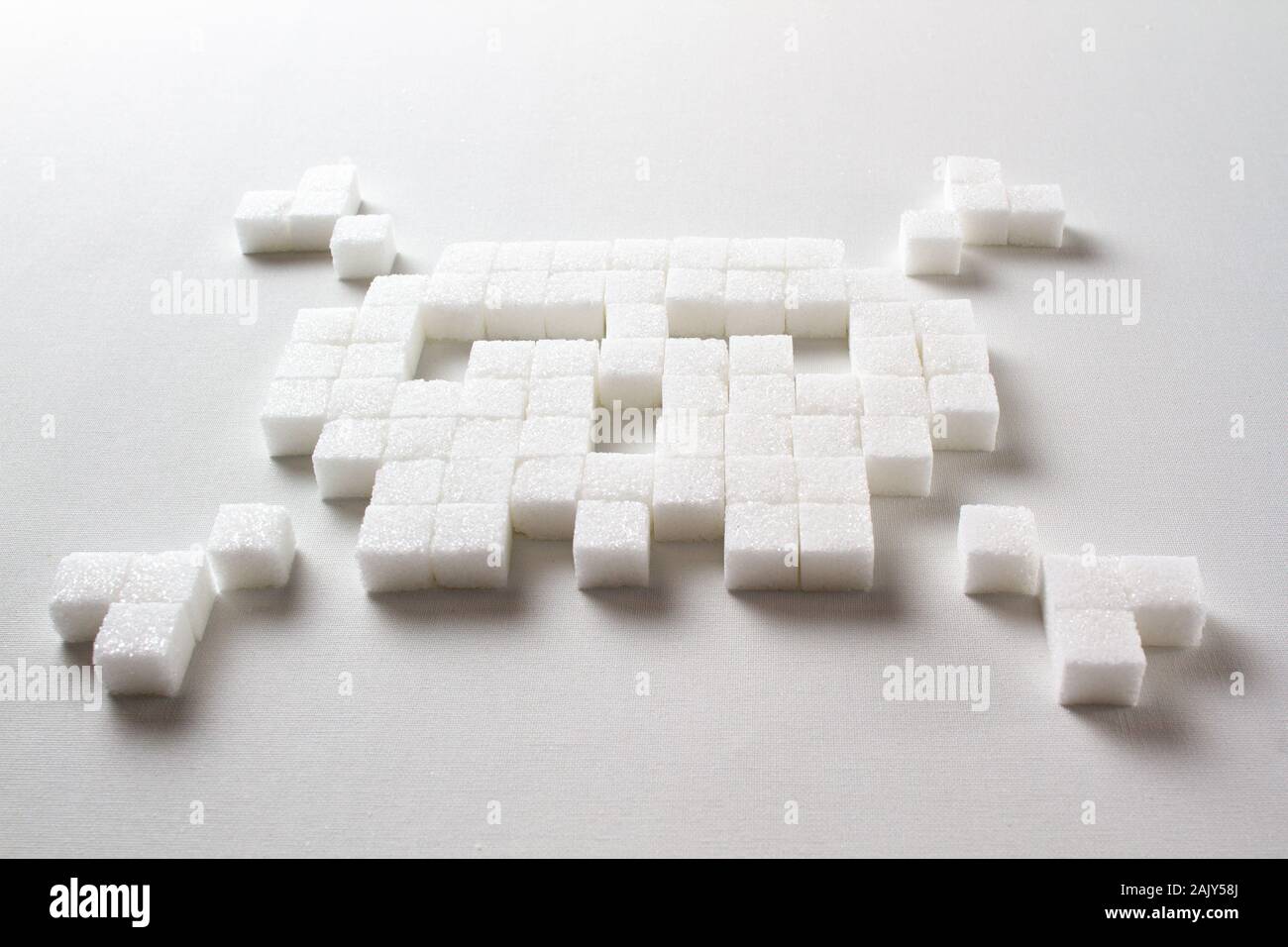 Pixel Art Totenkopf aus Zuckerwürfeln auf weißem Hintergrund symbolisiert ungesunde Nahrung Stockfoto