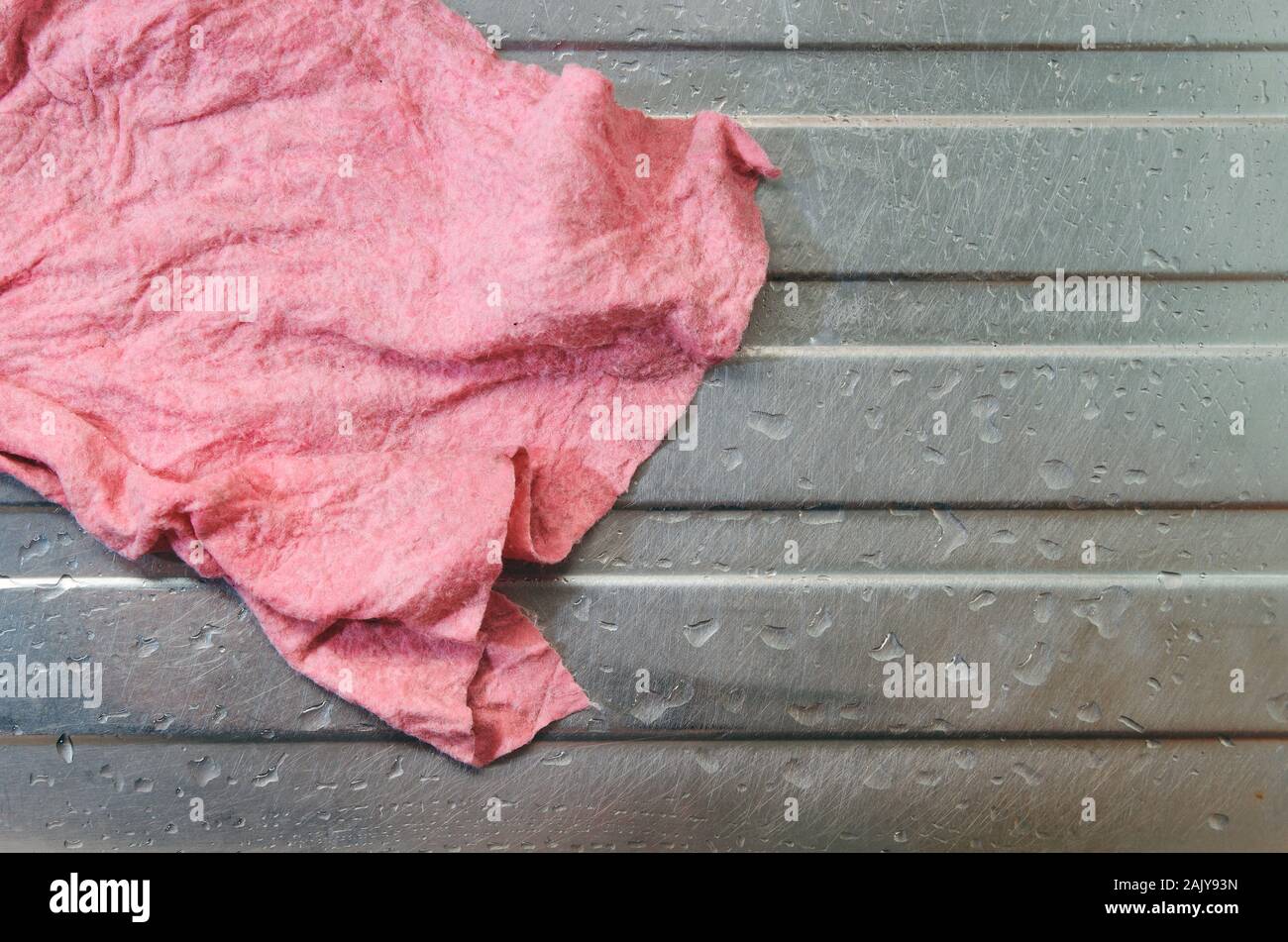 Single nassen Schmutz verwendet rosa Geschirrtuch (waschlappen). Auf einem  Edelstahl Spülbecken mit Wassertropfen herum platziert. Keine Menschen,  echte raw geschossen Stockfotografie - Alamy