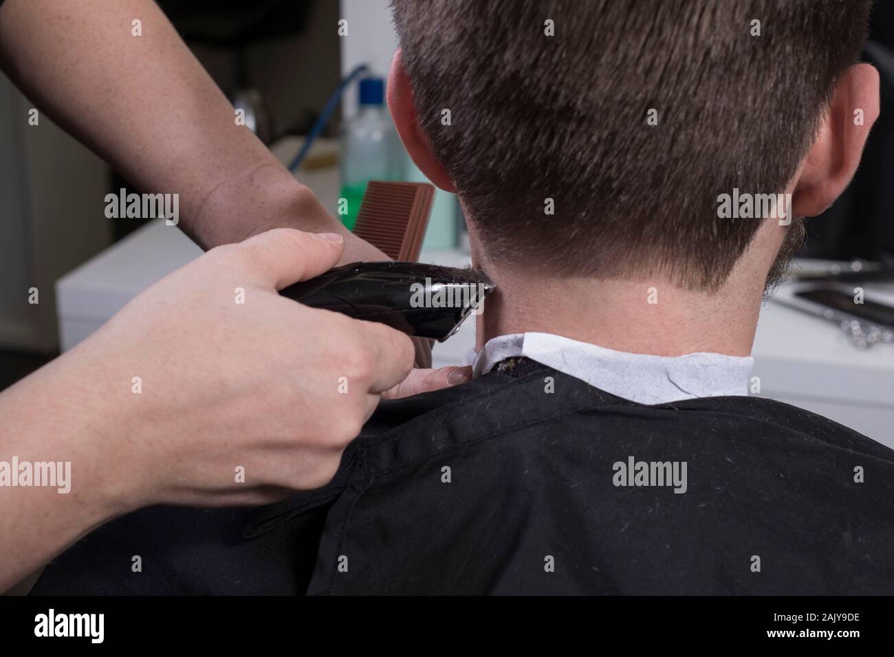 Friseur schneidet die Haare mit einem Langhaarschneider für einen jungen  Mann mit einem Bart. Nahaufnahme eines Master haircutting männliche Haar. Haare  schneiden in den Tempelanlagen von einem Kerl. B Stockfotografie - Alamy
