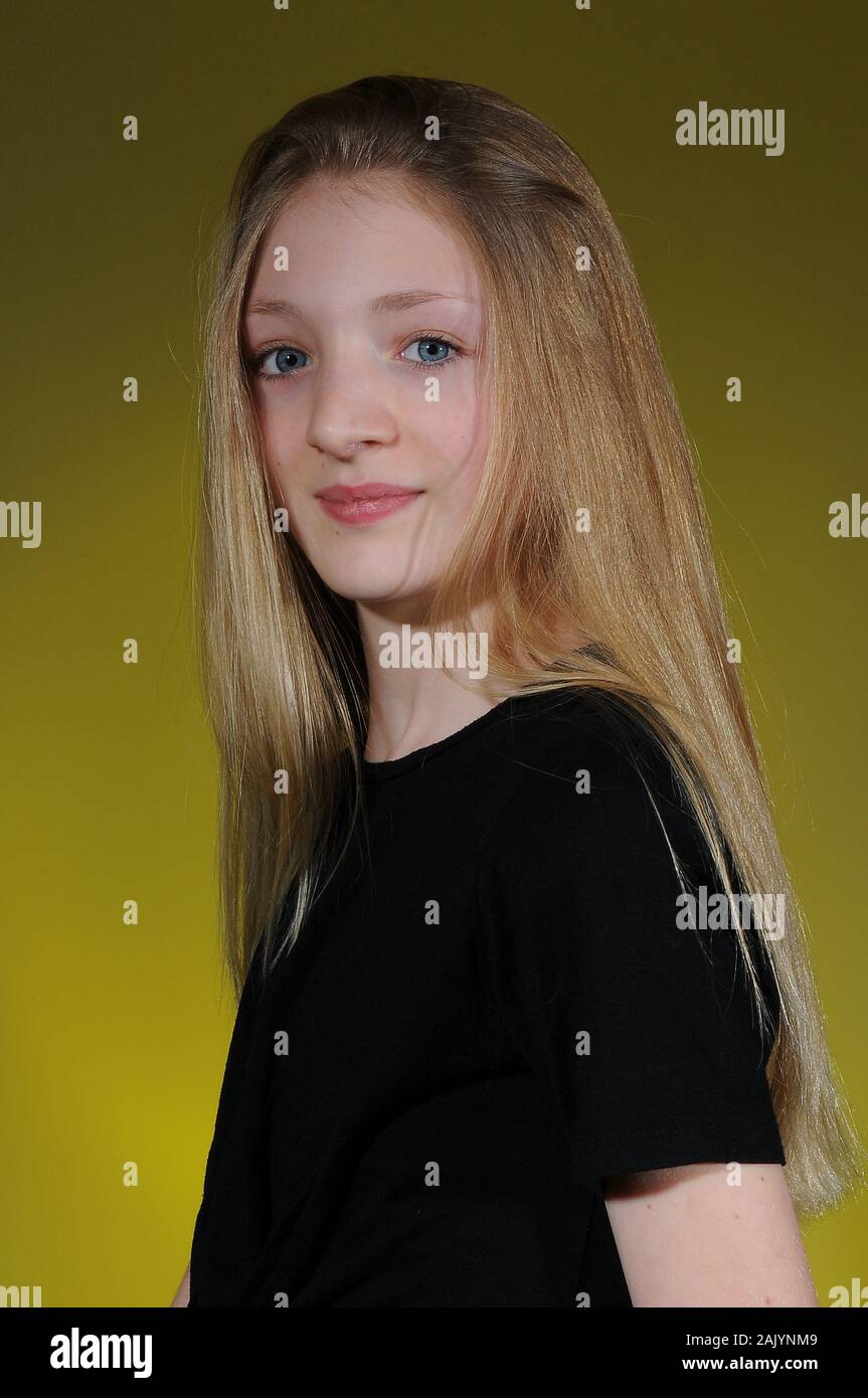 Hübsche blonde Kaukasischen Jugendmädchen in einem schwarzen T-Shirt auf einem hellen abgestuften Hintergrund isoliert Stockfoto