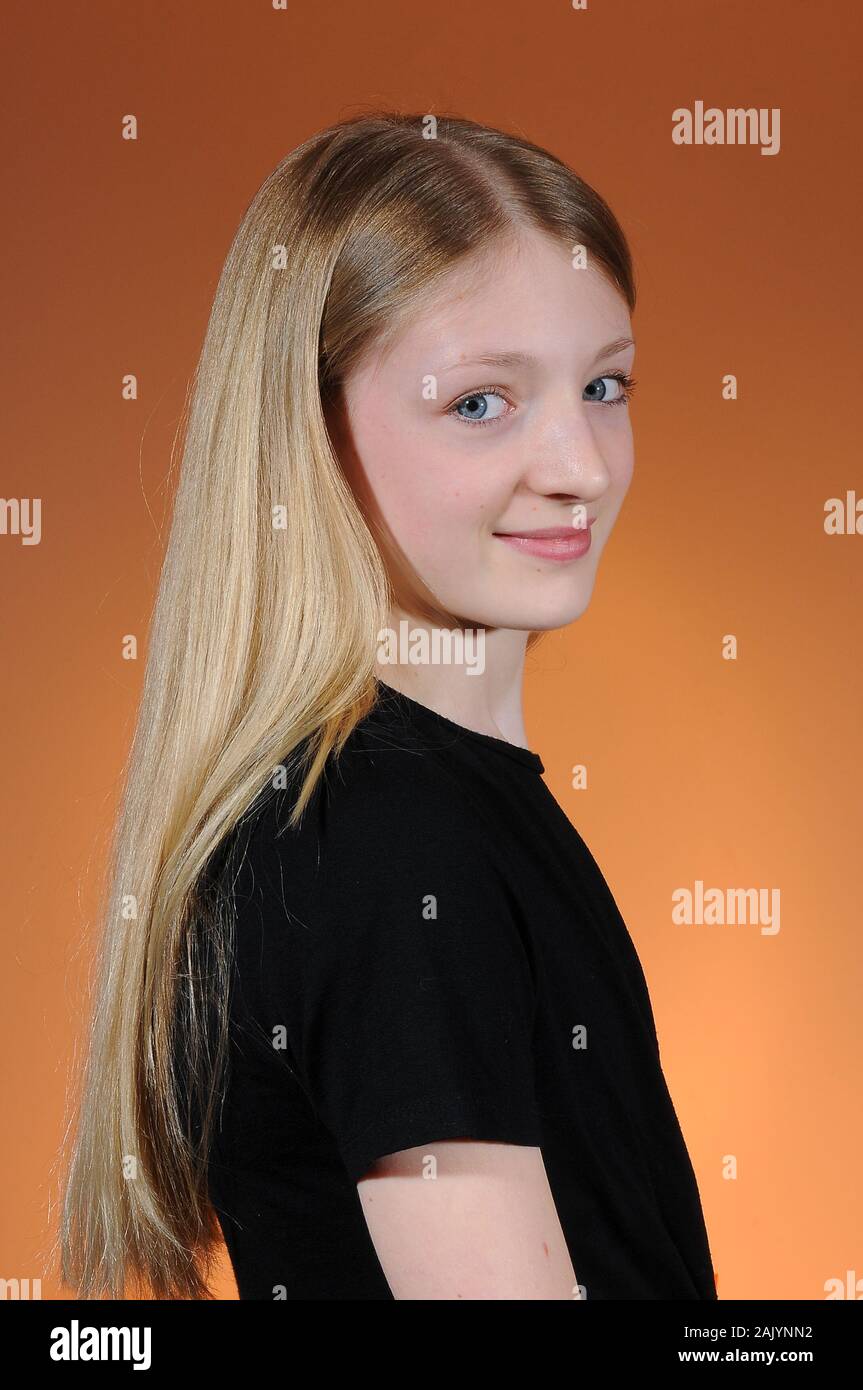 Hübsche blonde Kaukasischen Jugendmädchen in einem schwarzen T-Shirt auf einem hellen abgestuften Hintergrund isoliert Stockfoto