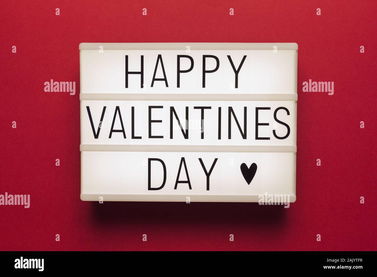 Foto eines weißen Licht, mit rotem Hintergrund und schwarzer Schrift mit dem Text 'Happy Valentines Day" Stockfoto