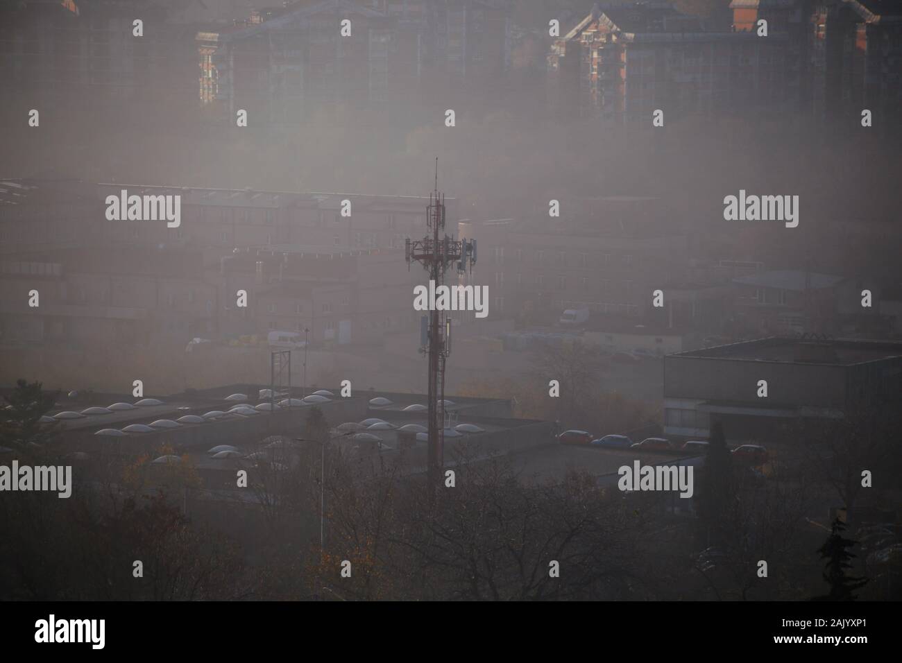 Wintermorgen Blick auf Landschaft von Häusern, Gebäuden und Telecommunication Tower mit Nebel. Schädliche Emissionen und Abgase in die Luft. Stockfoto