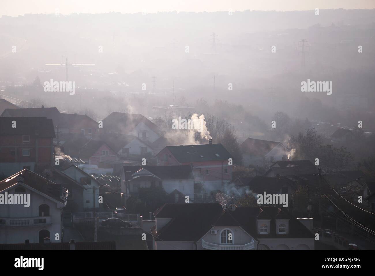 Rauchende Schlote auf Dächer der Häuser gibt Rauch, Smog bei Sonnenaufgang, Schadstoffe geben Sie Atmosphäre. Schädliche Emissionen und Abgase in die Luft. Stockfoto