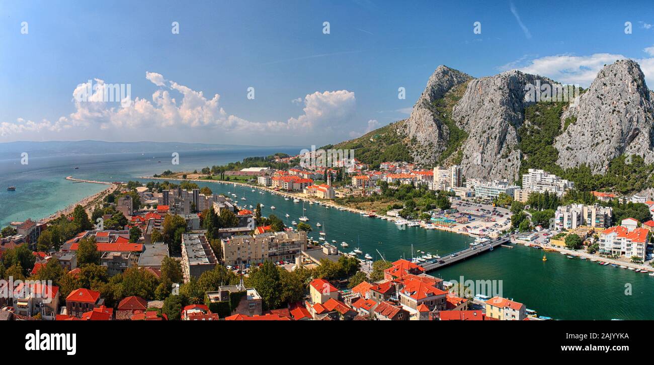 Omis Stadt (Kroatien) Skyline, Küste, Fluss mit Booten, felsige Berge, sonnig mit Wolken Stockfoto