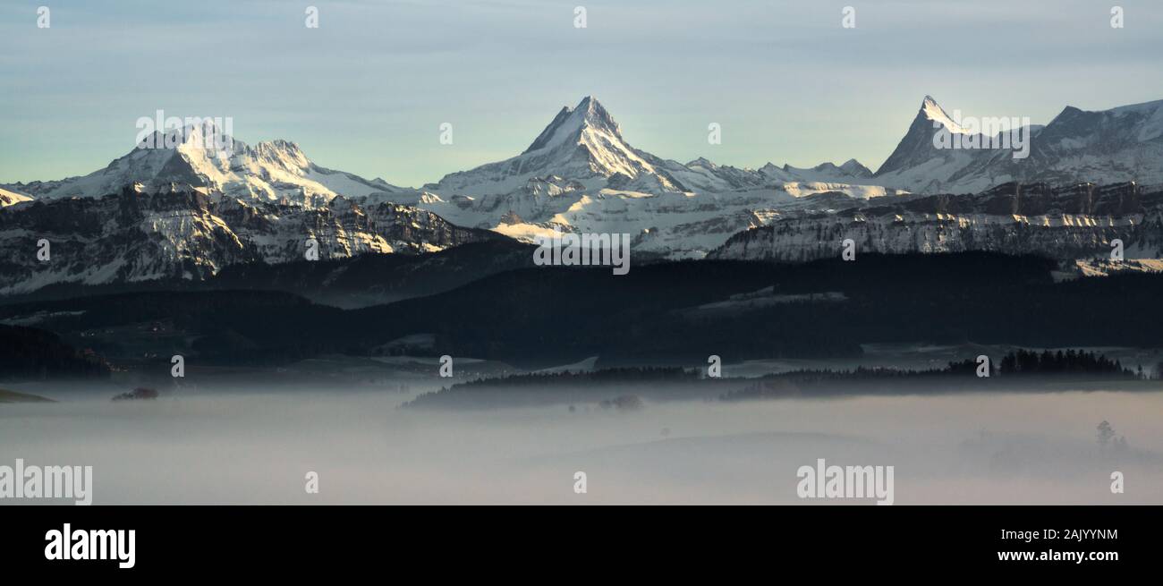 Beeindruckende Bergwelt der Schweiz in Schnee während einer nebligen Tag bedeckt im Winter Stockfoto