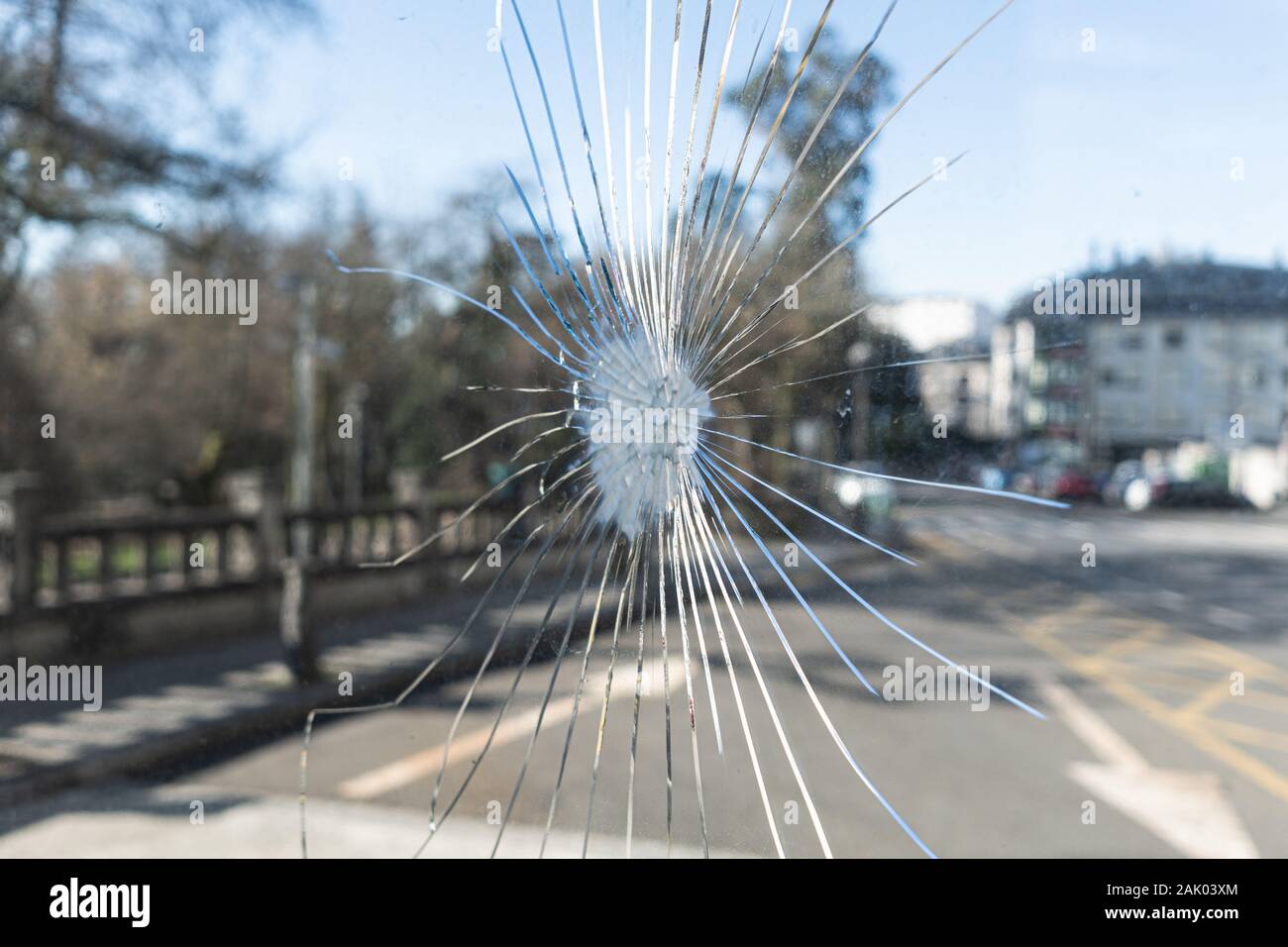 Zerbrochenes Glas mit Rissen und verschwommenes Stadt Hintergrund. Vandalismus Konzept oder soziale Probleme Stockfoto
