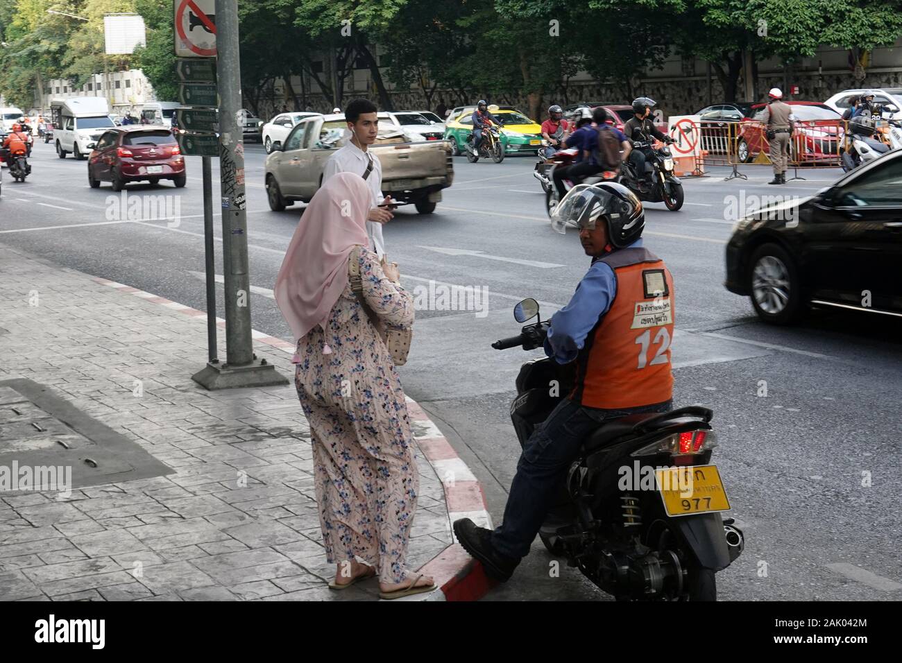 Bangkok, Thailand - 26. Dezember 2019: Muslimische Frau zahlt Fahrpreis für Motorradtaxifahrer nach der Fahrt. Stockfoto