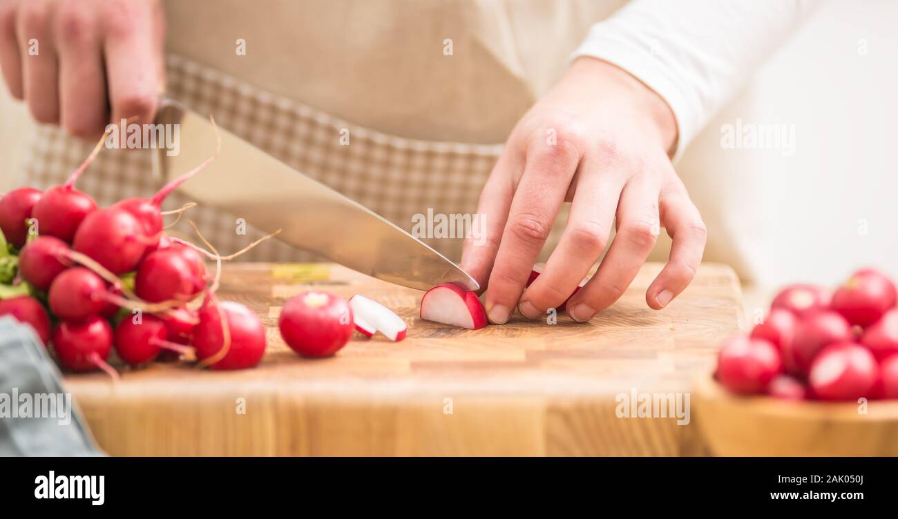 Frau schneiden frische Radieschen zu Hause in der Küche Stockfoto