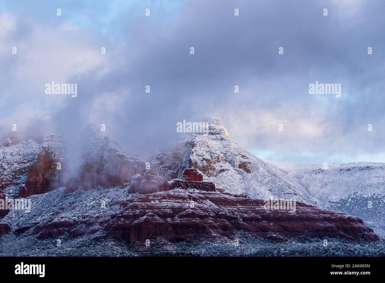 Herrliche Winterlandschaft von Sedona Berge mit Schnee mit Morgennebel und Nebel steigt aus den roten Felsen bedeckt. Stockfoto