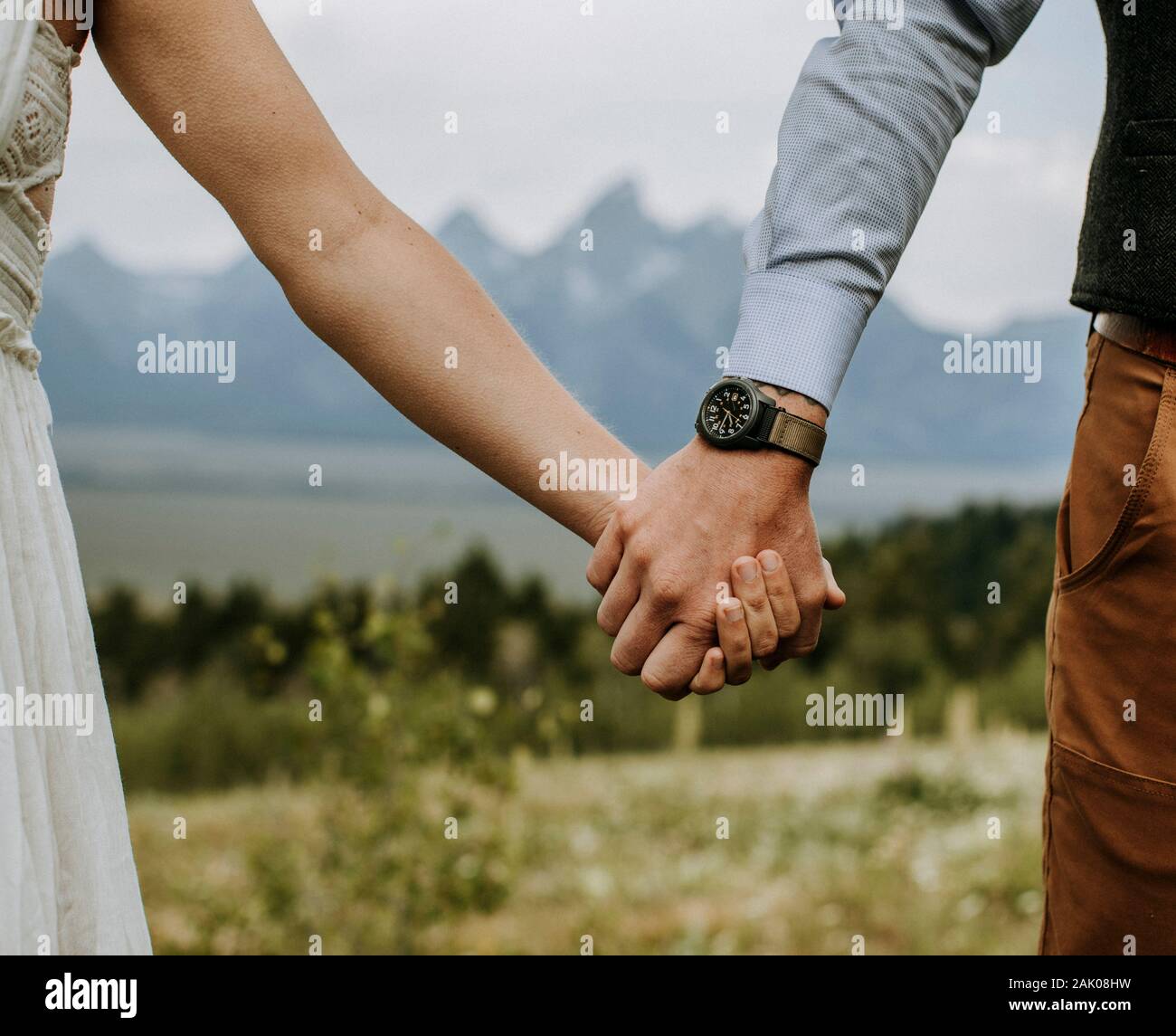 Braut und Bräutigam halten die Hände vor Grand Teton, Wyoming Stockfoto
