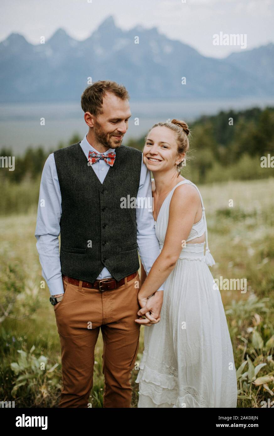 Brautpaar und Brautpaar halten sich im Blumenfeld Stockfoto