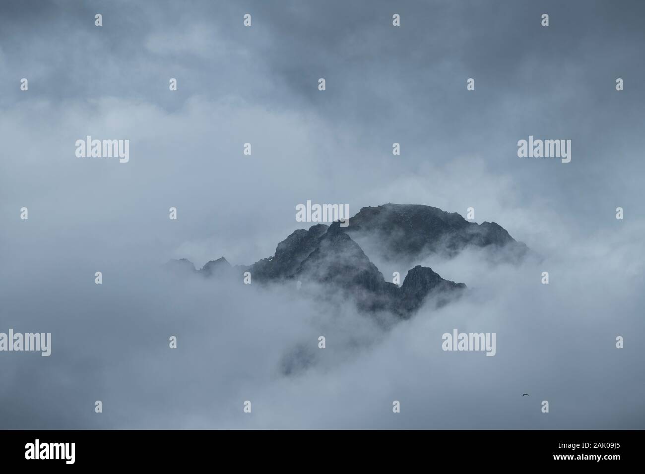 Weit entfernten Berg entsteht aus dicken Wolken, Reine, Moskenesøy, Lofoten, Norwegen Stockfoto