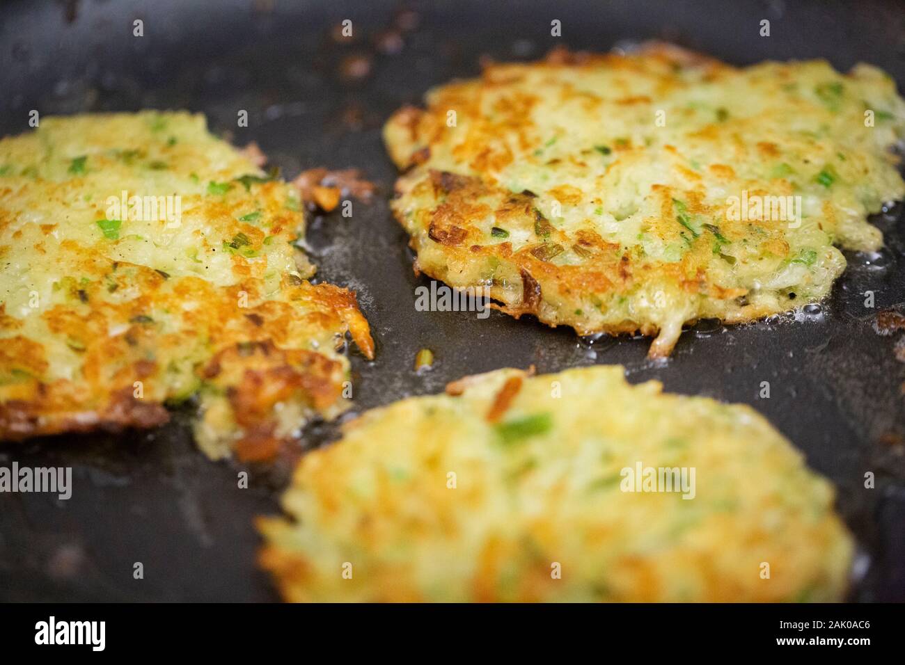 Nahaufnahme von drei Latkes Braten in Öl während der Chanukkah Nahrungszubereitung Stockfoto