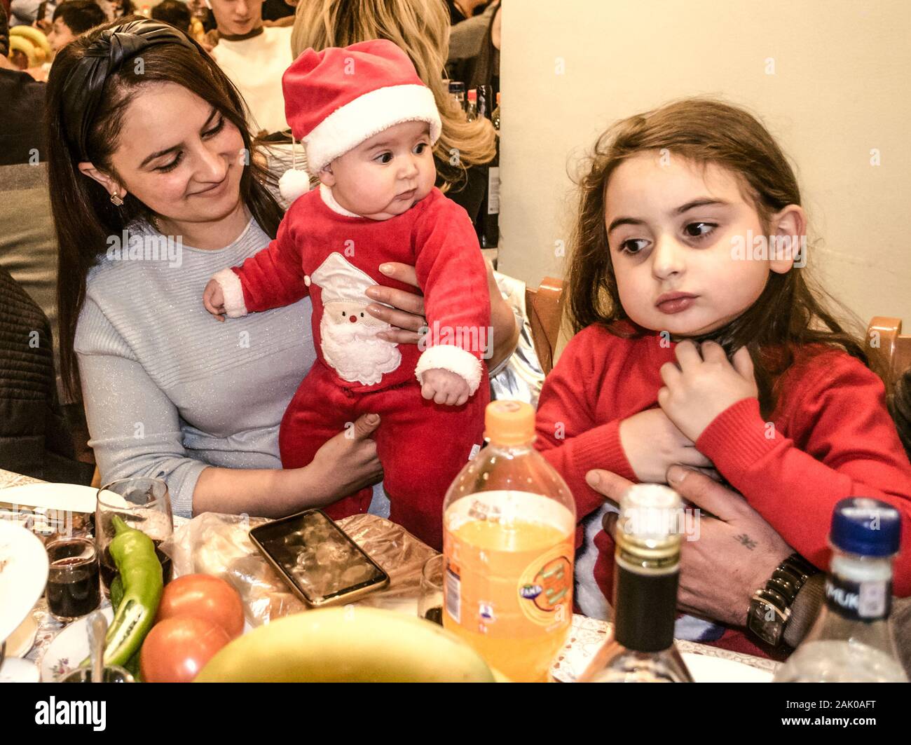 Dilijan, Armenien, Januar 01, 2019: Kinder in das Kostüm von Santa Claus mit ihrer Mutter zu einem festlichen Tisch im Sanatorium 'Mountain Armeni sitzen Stockfoto