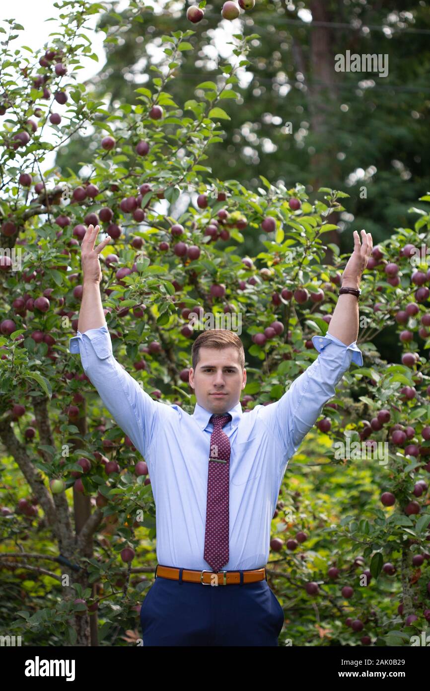 Selbstbewusster Mann wirft Arm voller Äpfel in die Luft. Stockfoto
