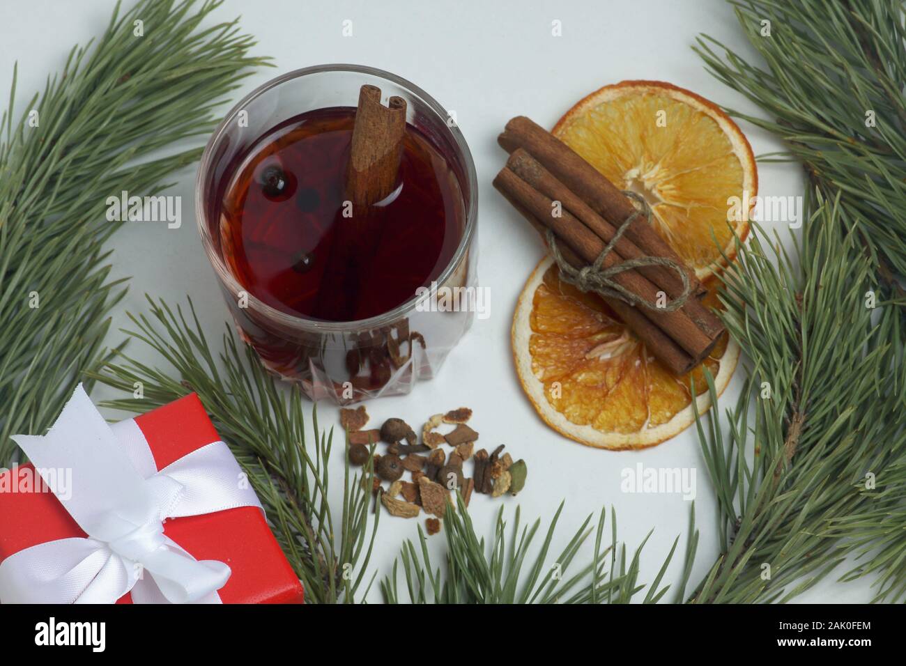Glas Glühwein, Zimtstangen, Gewürz, orange Chips und einem Geschenkkarton mit Tanne Ast auf weißem Hintergrund Nahaufnahme eingerahmt. Flach, Bild enthält. Stockfoto