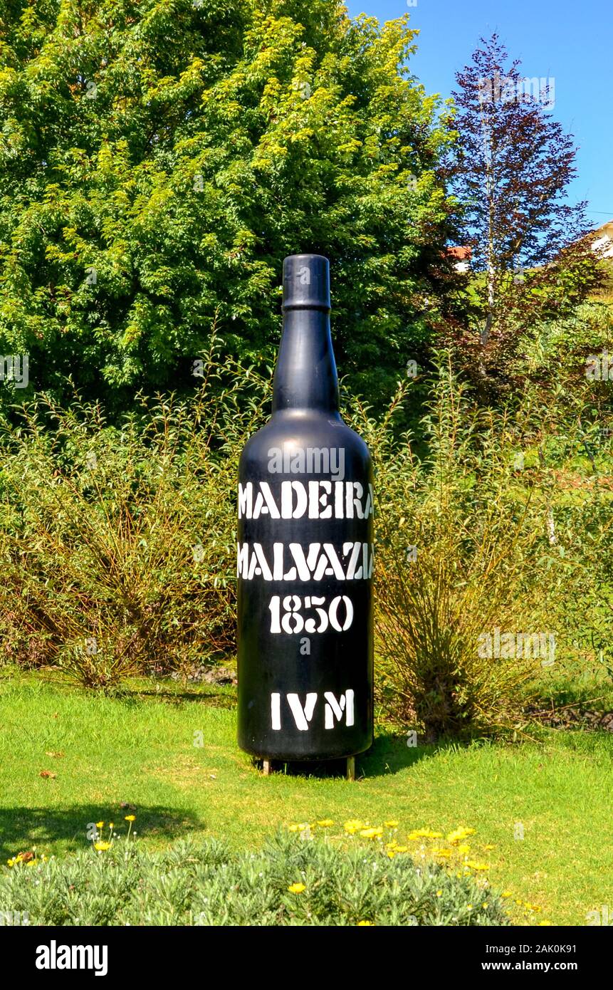 Santana, Madeira, Portugal - Sep 24, 2019: Riesige Flasche Wein Madeira Wein als Exponat auf Madeira Themenpark. Große schwarze Flasche Wein im Freien umgeben von grünen Bäumen. Vertikale Foto. Stockfoto