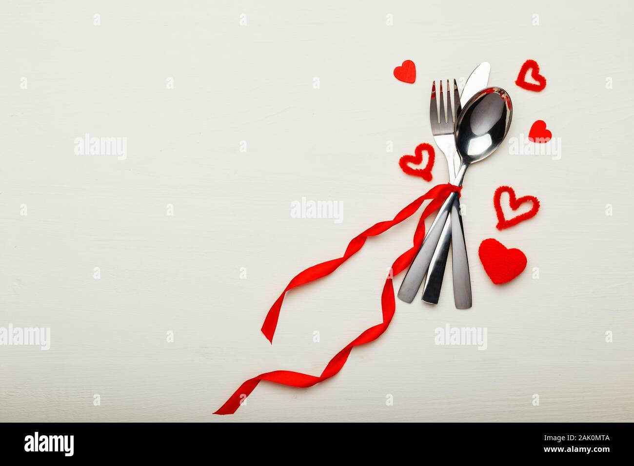 Besteck von Red Ribbon mit vielen roten Herzen am Valentines Tag müde. Festliche Tafel Einstellung auf eine weiße Holztisch. Abendessen im Restaurant Stockfoto