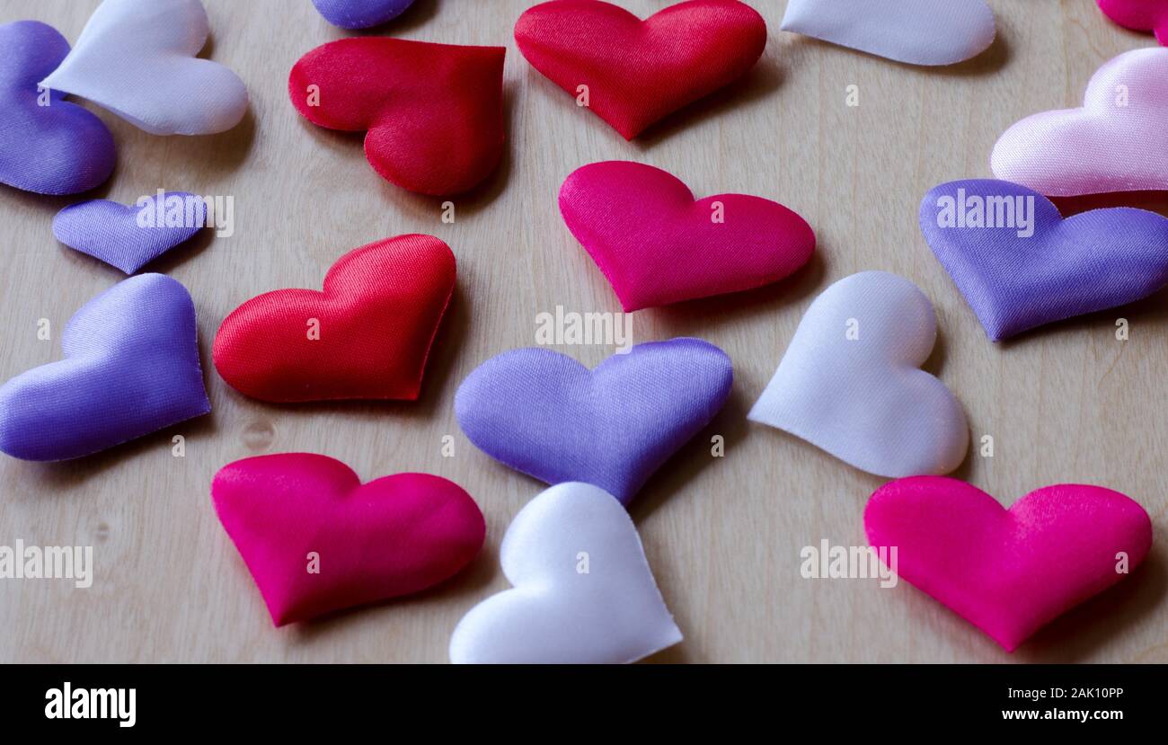 Herzen in verschiedenen Farben und Größen auf hölzernen Tisch Stockfoto