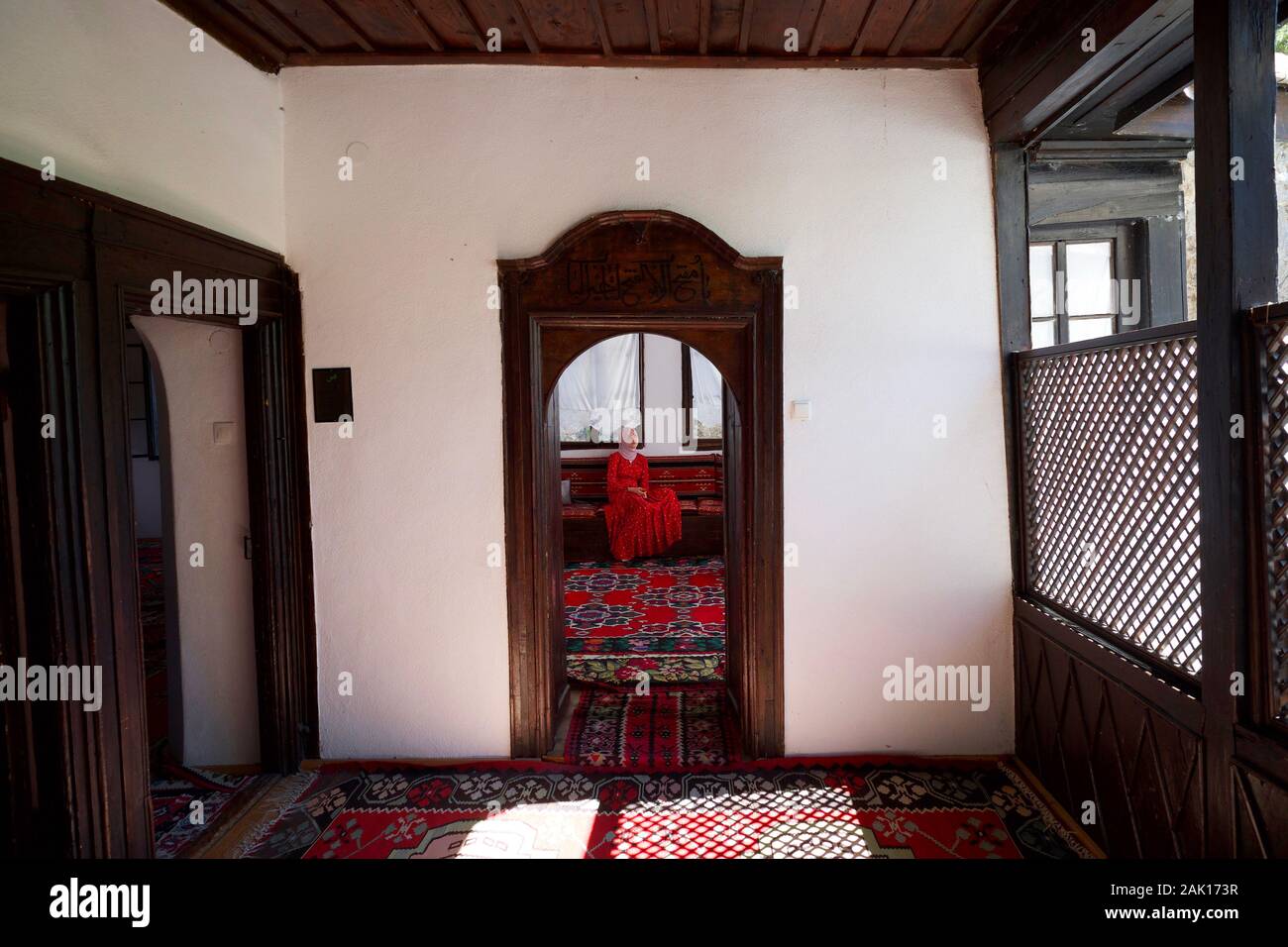 Eine Frau in einem roten Kleid sitzt in einem Raum an der Blagaj Tekija Kloster, in der Nähe von Mostar, Bosnien Stockfoto