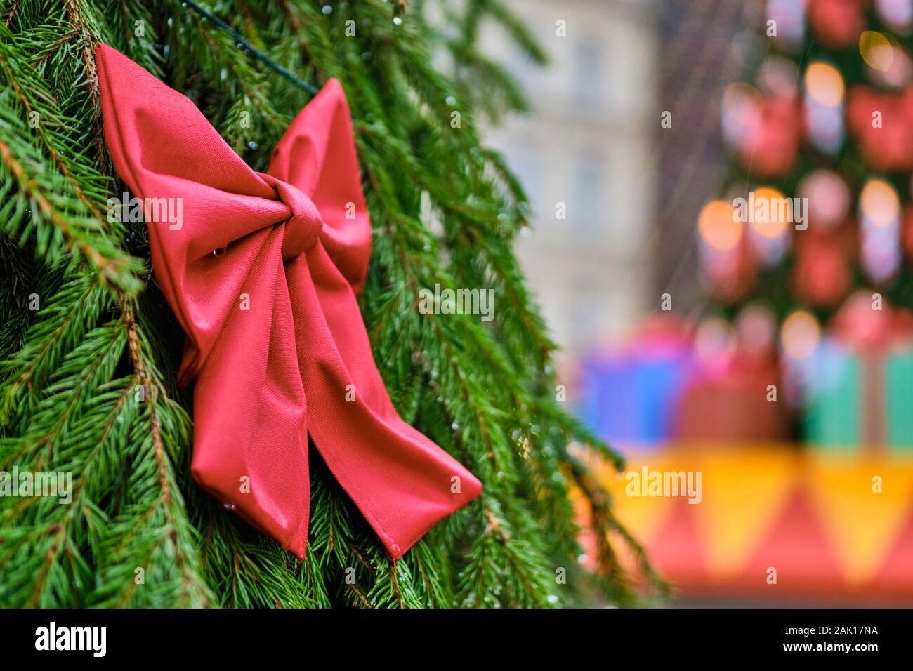 Weihnachten Dekoration in Form eines roten Bogen mit einem gelben Ball vor dem Hintergrund einer unscharfen Baum mit Lichtern. Close Up. Stockfoto
