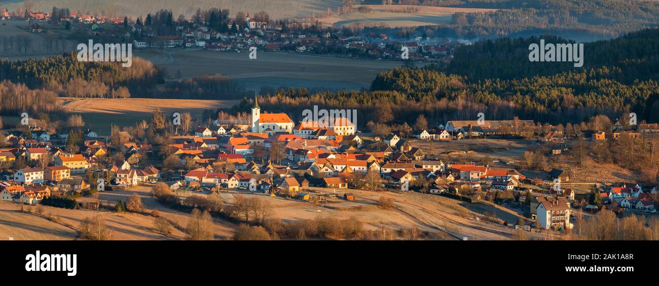 Südböhmisches Dorf mit Kirche - von aufsteigender Sonne angezündet, ländliche Landschaft mit Wald, Feldern und Wiesen rund um (Sobenov, Tschechien) Stockfoto