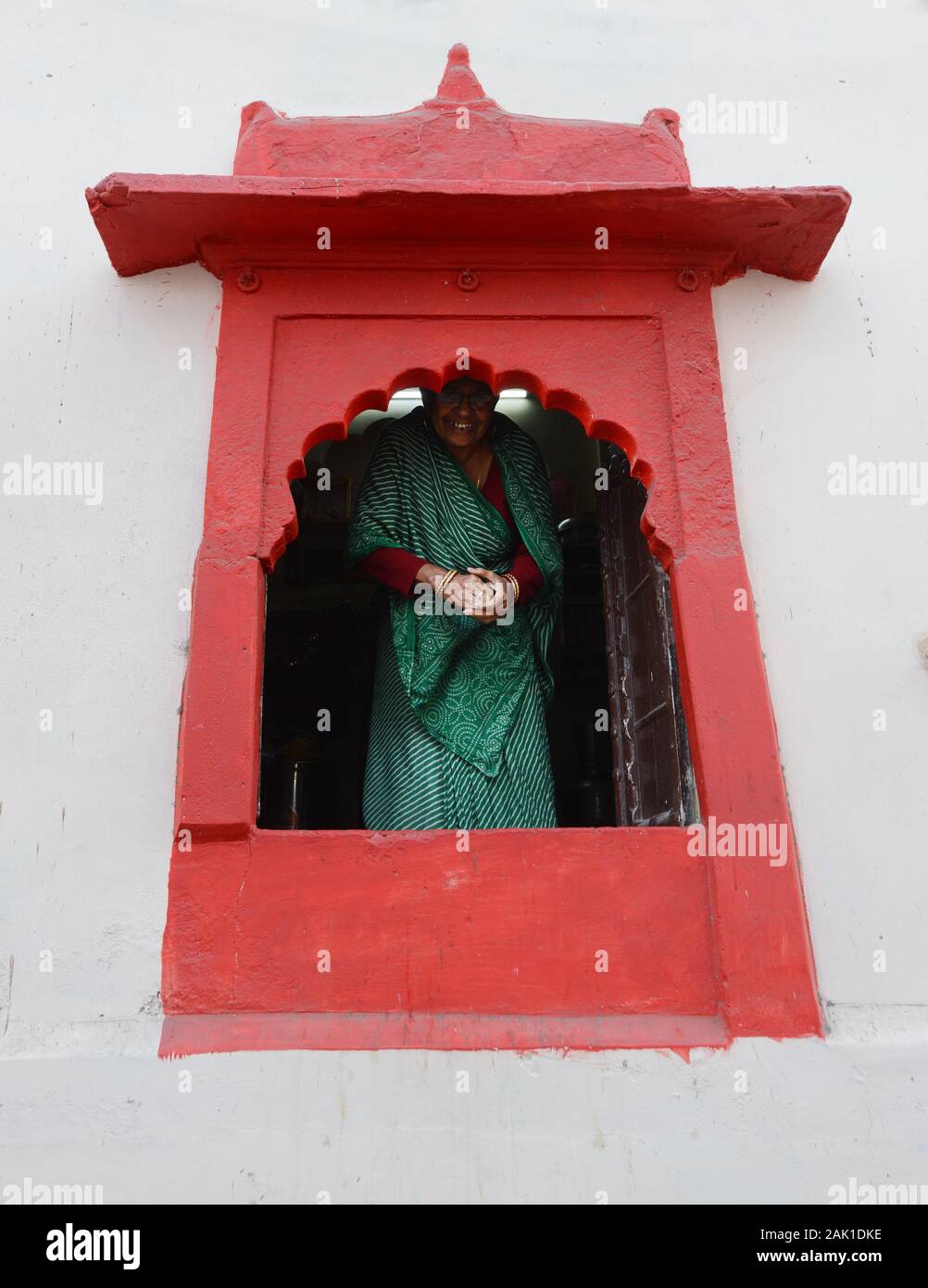 Eine Indianerin, die durch ein buntes Fenster in der Altstadt von Jodhpur, Indien, pinkelt. Stockfoto