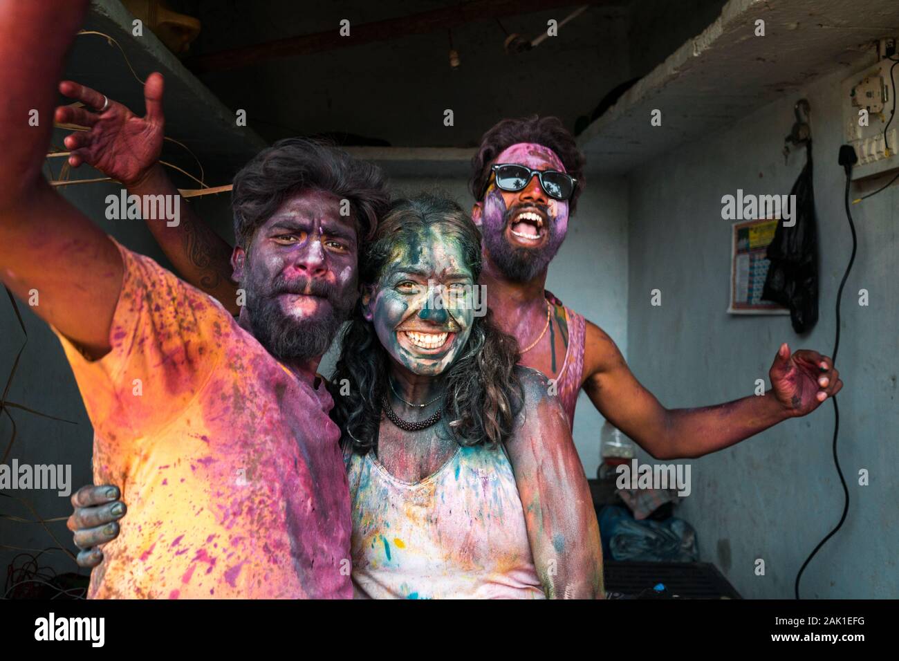 Hampi, Indien - 07. April 2019: Aufgeregter junger indischer DJ und Touristen, die sich in bunten Pigmenten die Hände schütteln, um das Heilige Fest im ländlichen Dorf Hanuman Halli, Karnatak, zu feiern Stockfoto