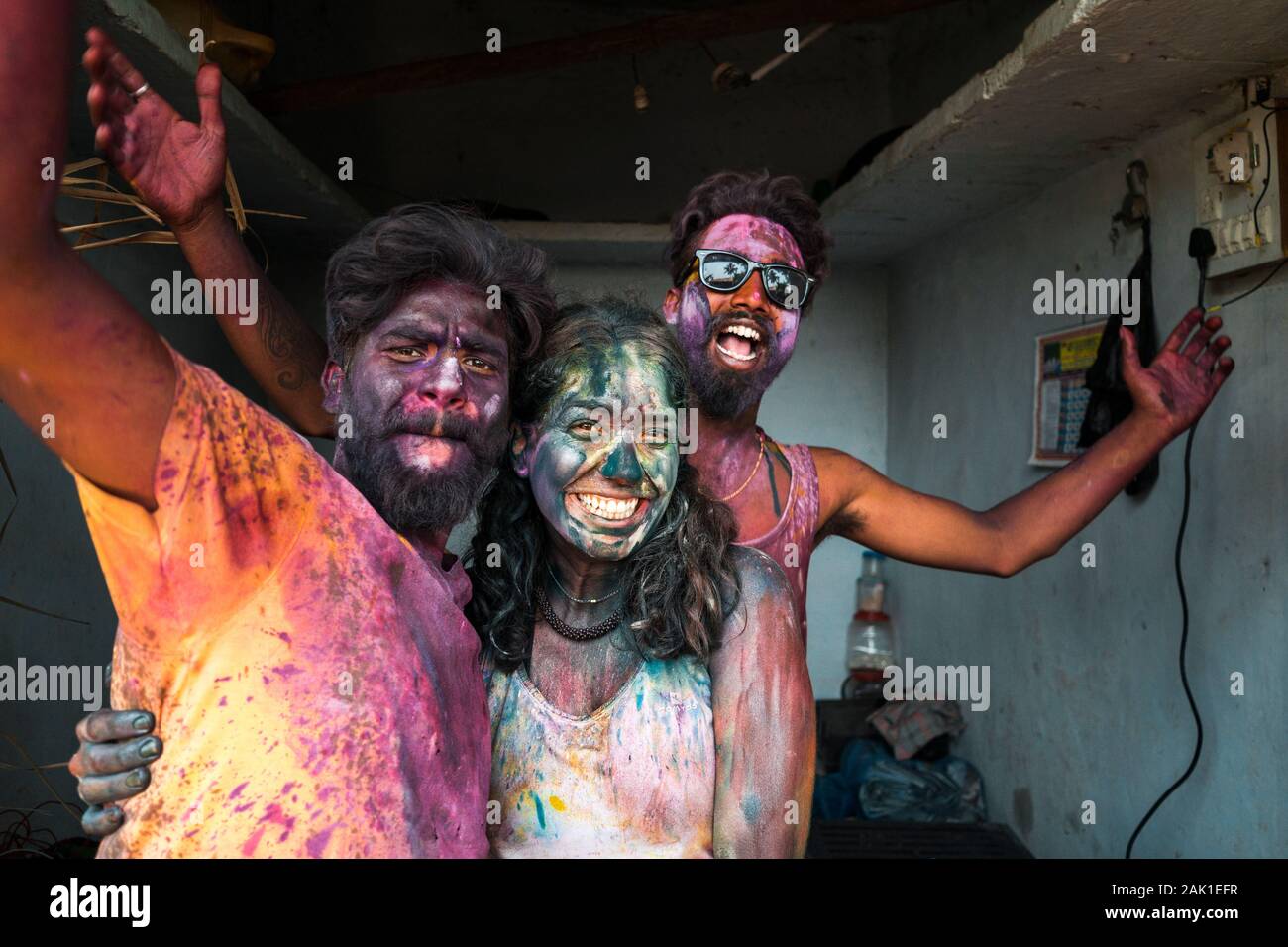 Hampi, Indien - 07. April 2019: Aufgeregter junger indischer DJ und Touristen, die sich in bunten Pigmenten die Hände schütteln, um das Heilige Fest im ländlichen Dorf Hanuman Halli, Karnatak, zu feiern Stockfoto