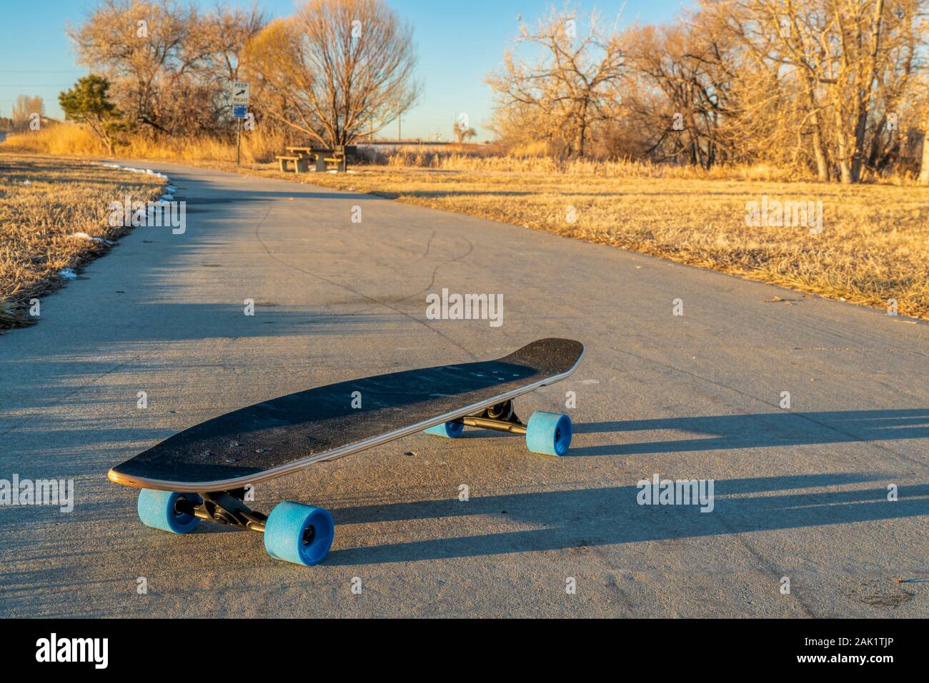 Kreuzfahrt Longboard mit blauen Räder auf einer asphaltierten Radweg im  Winter Landschaft im Norden von Colorado - Boyd Lake State Park  Stockfotografie - Alamy