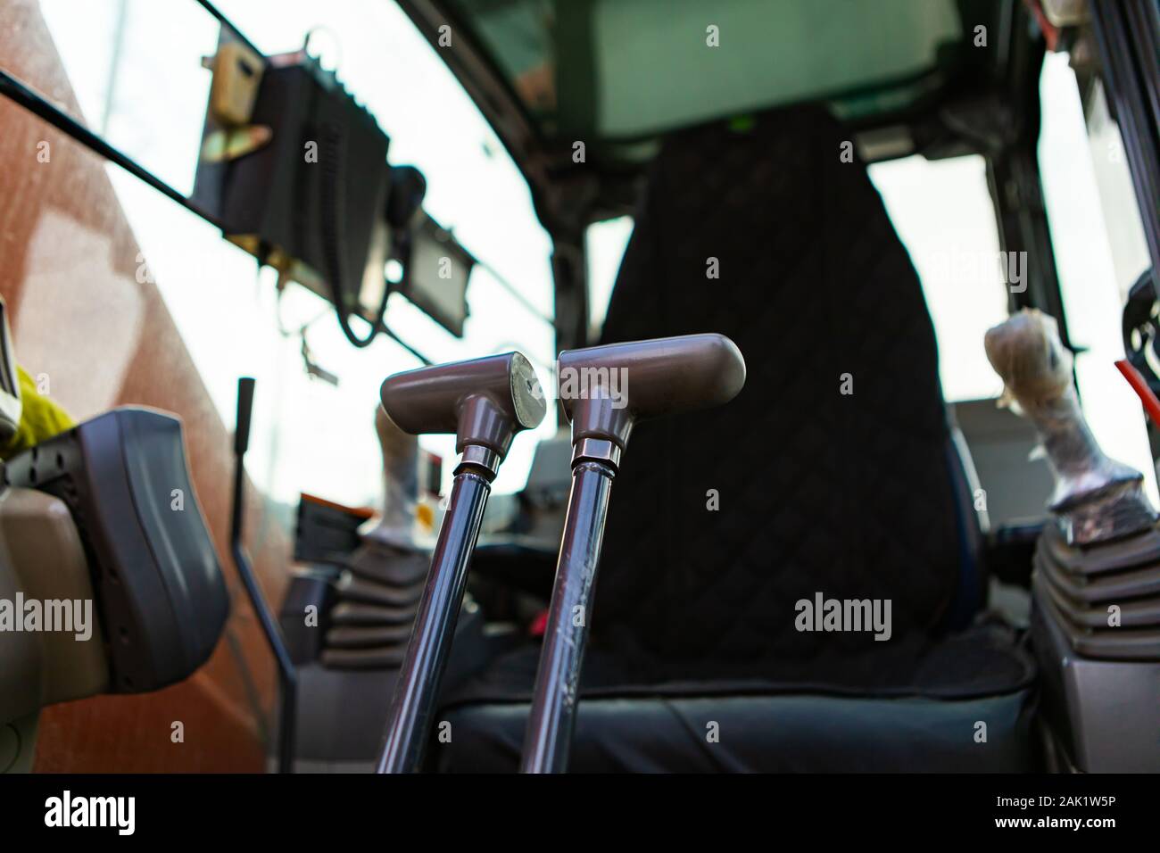 Low Angle View in der Kabine eines Mini Bagger, die Steuerhebel hydraulische Arme mit Fahrersitz im Hintergrund und kopieren Raum zu bedienen Stockfoto
