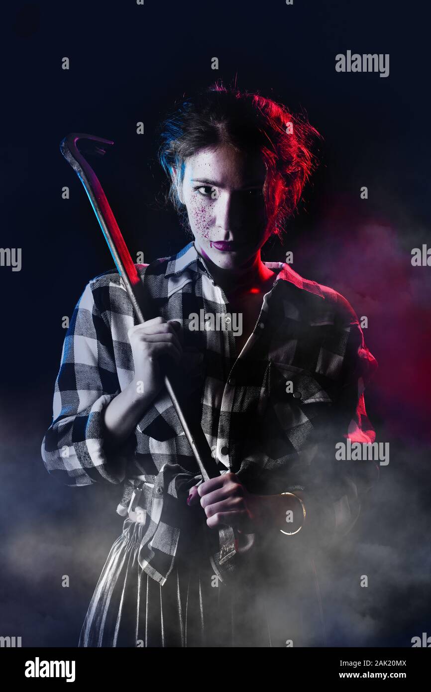 Blutiger ernst junge Frau mit Brecheisen in dunklen Blick auf Kamera getonten Bild Stockfoto