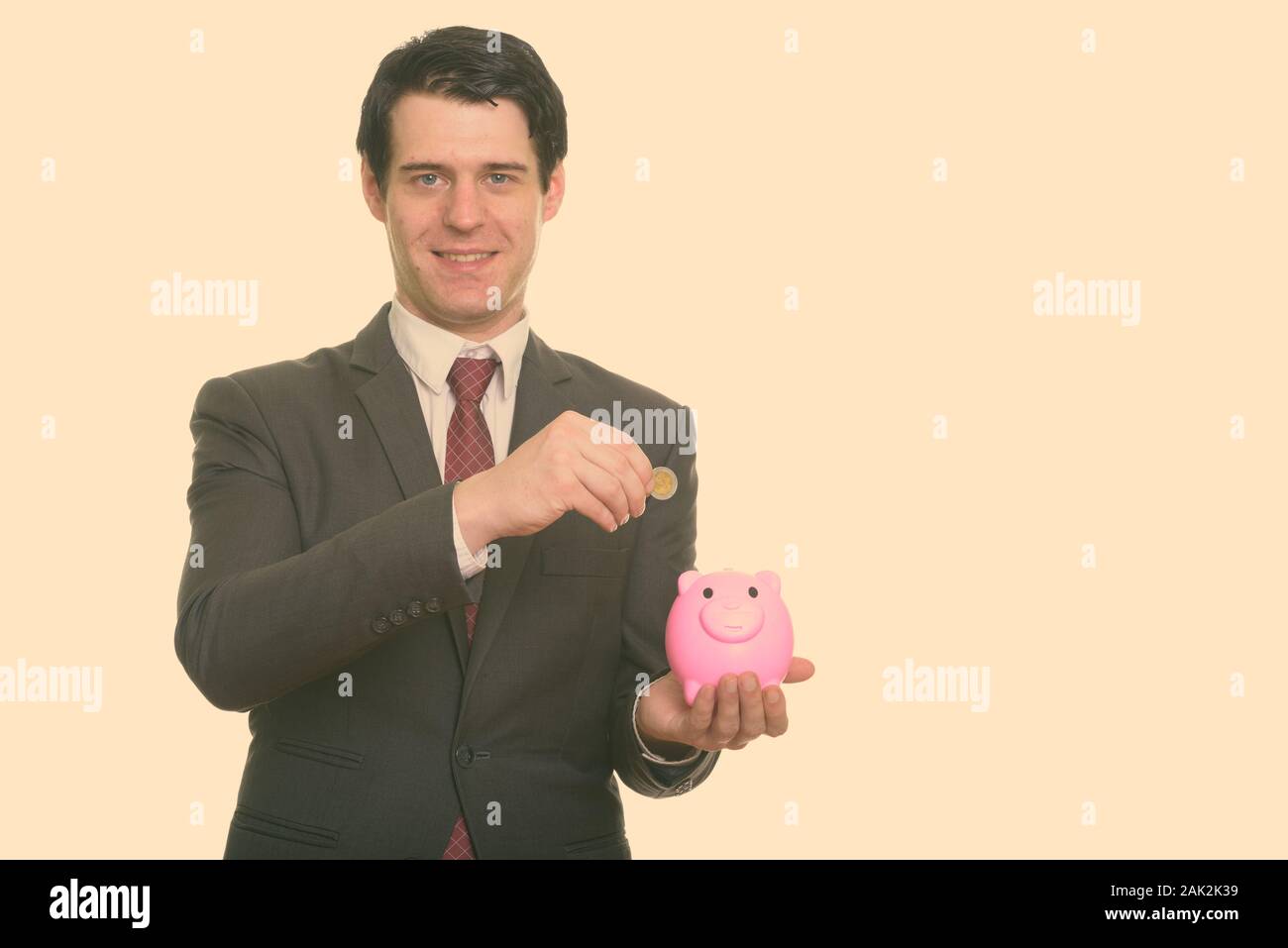 Studio geschossen von glücklich, Geschäftsmann, Lächeln, während sie Münze in piggy Bank Stockfoto