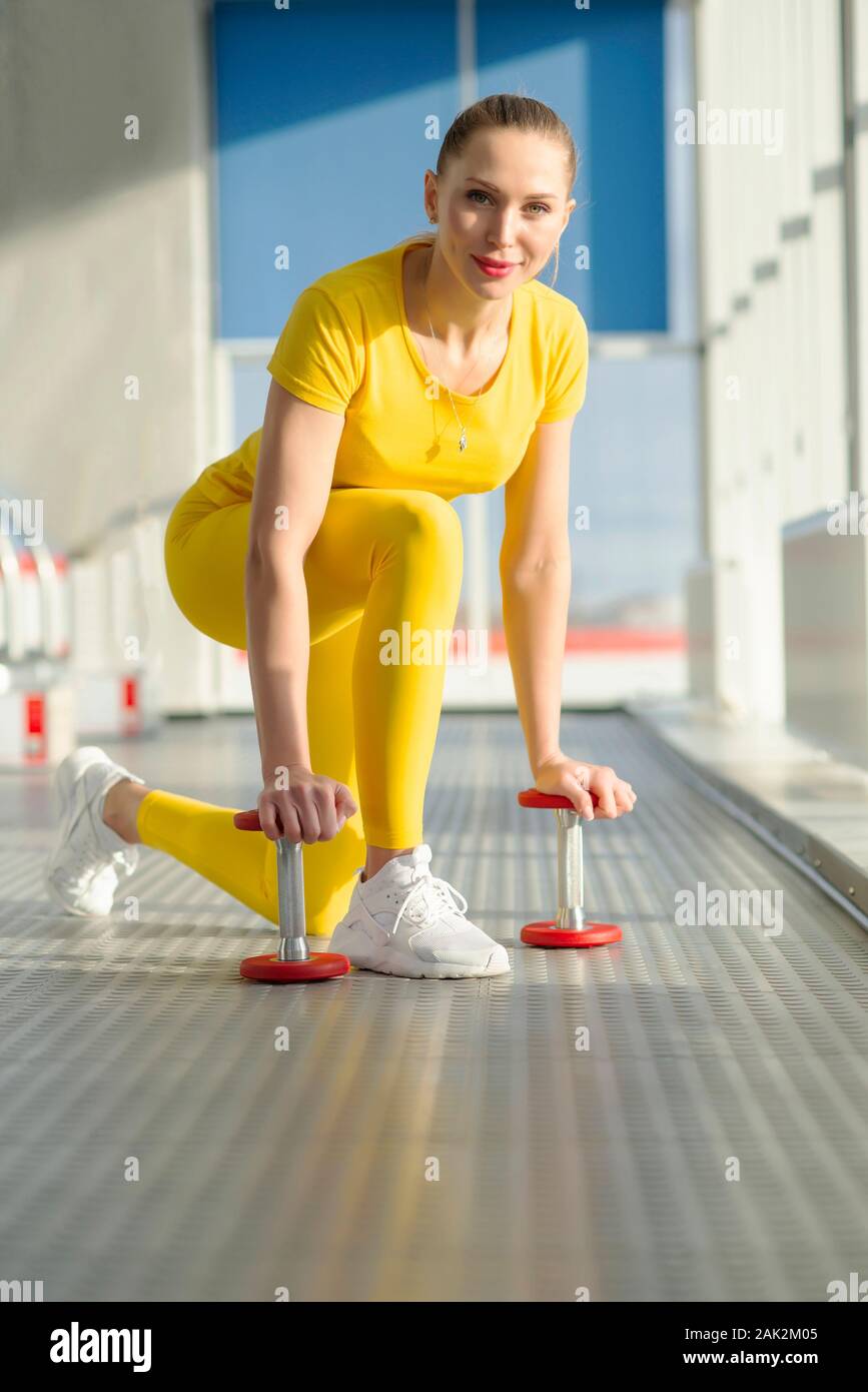 Körperlich fit Frau am Fitnessraum mit Hanteln bereit, ihre Arme und Bizeps zu stärken Stockfoto