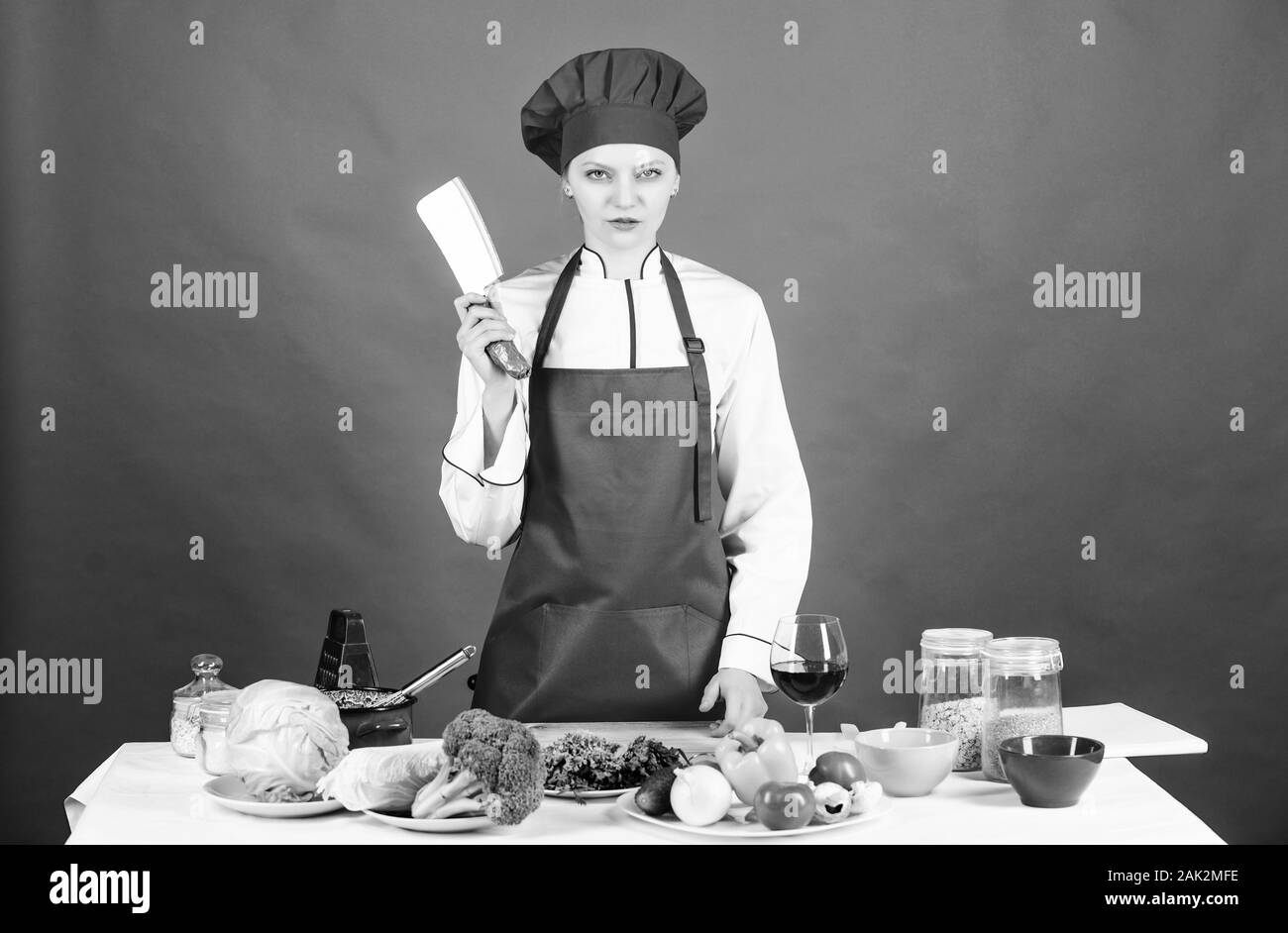 Frau Koch hat mit Messer. Menü im Restaurant. Diät. Schwere Frau Kochen gesund essen von Rezept. professioneller Koch auf rotem Hintergrund. Organische essen und Vegetarisch. Hausfrau. Stockfoto