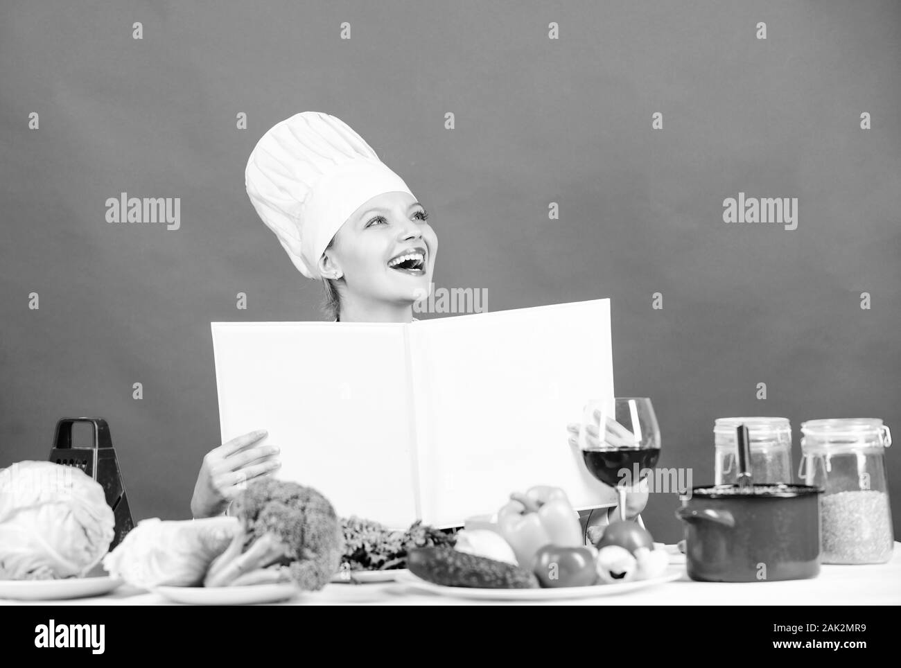 Bio und vegetarische Essen. Hausfrau. Menü im Restaurant. Diät. Frau Koch hat. professioneller Koch auf rotem Hintergrund. glückliche Frau Kochen gesund essen von Rezept. Vegetarische Konzept. Stockfoto