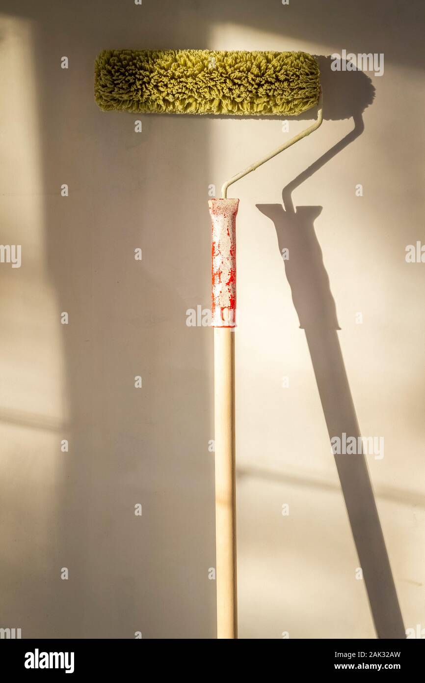 Grüne Farbe Roller steht gegen eine weiße Wand. Stockfoto