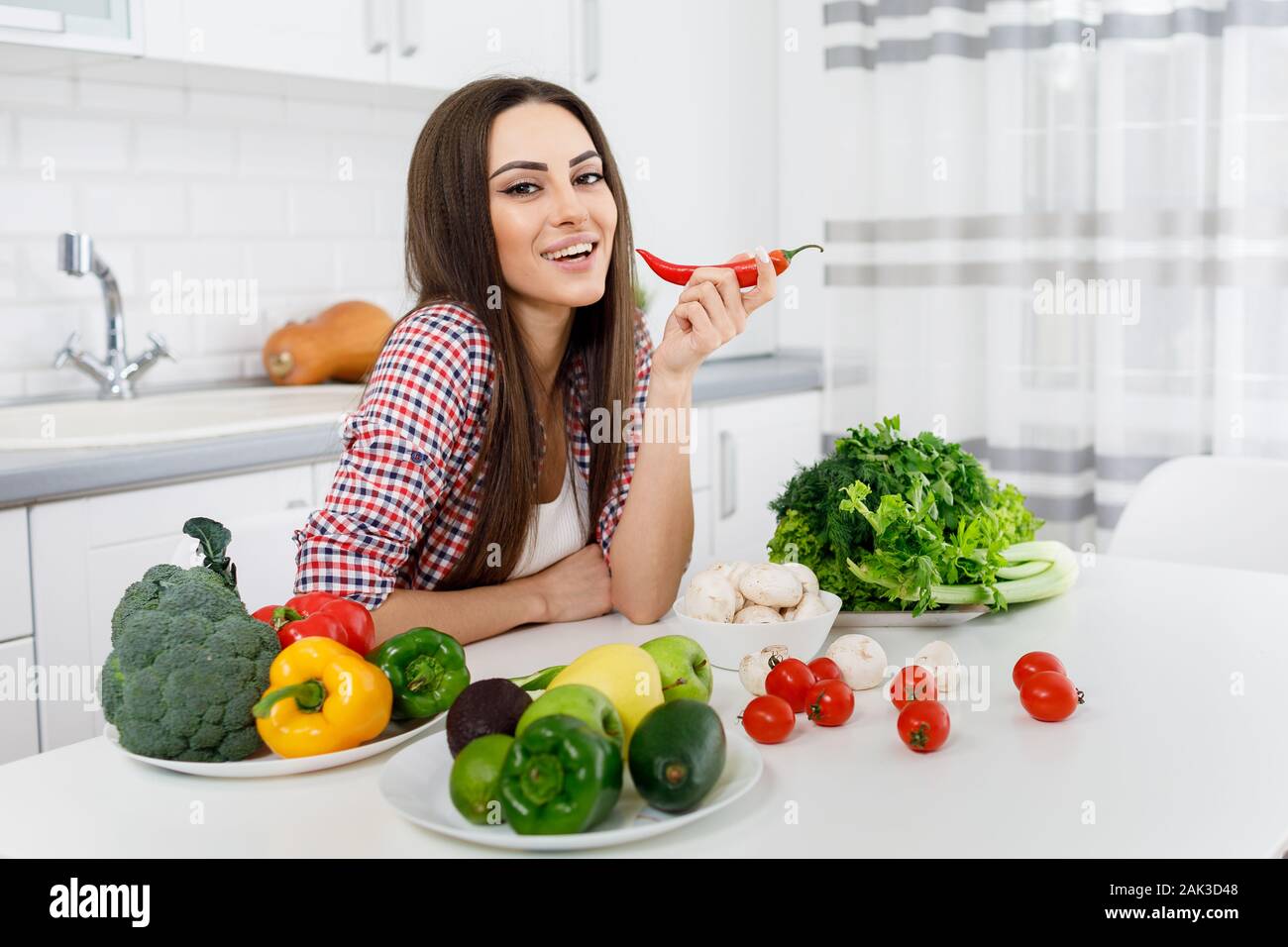 Schöne junge Brunette posing in eine Küche voller Greengrocery Stockfoto
