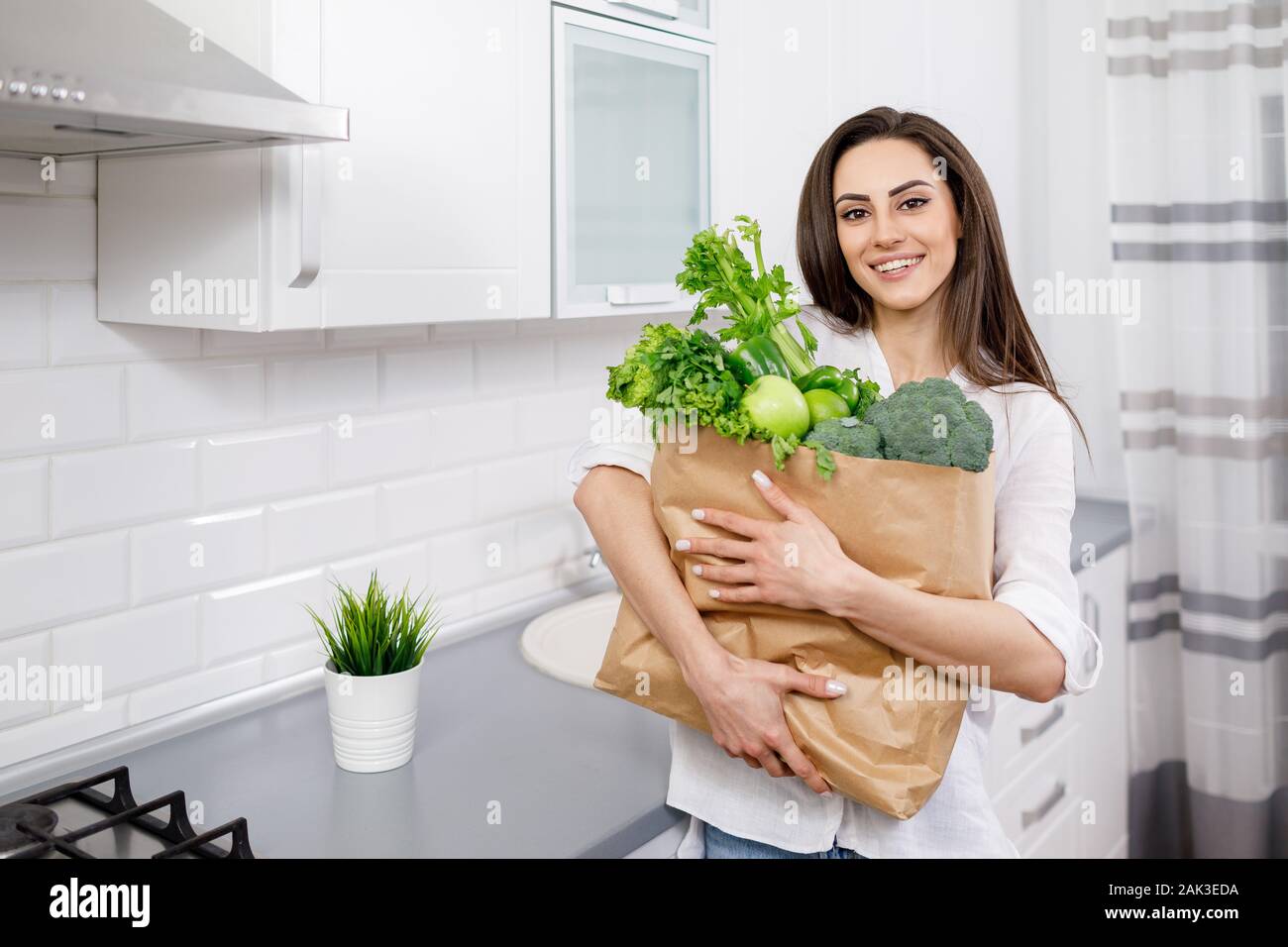 Junge Brünette Hausfrau mit Papier Beutel der Greengrocery Stockfoto