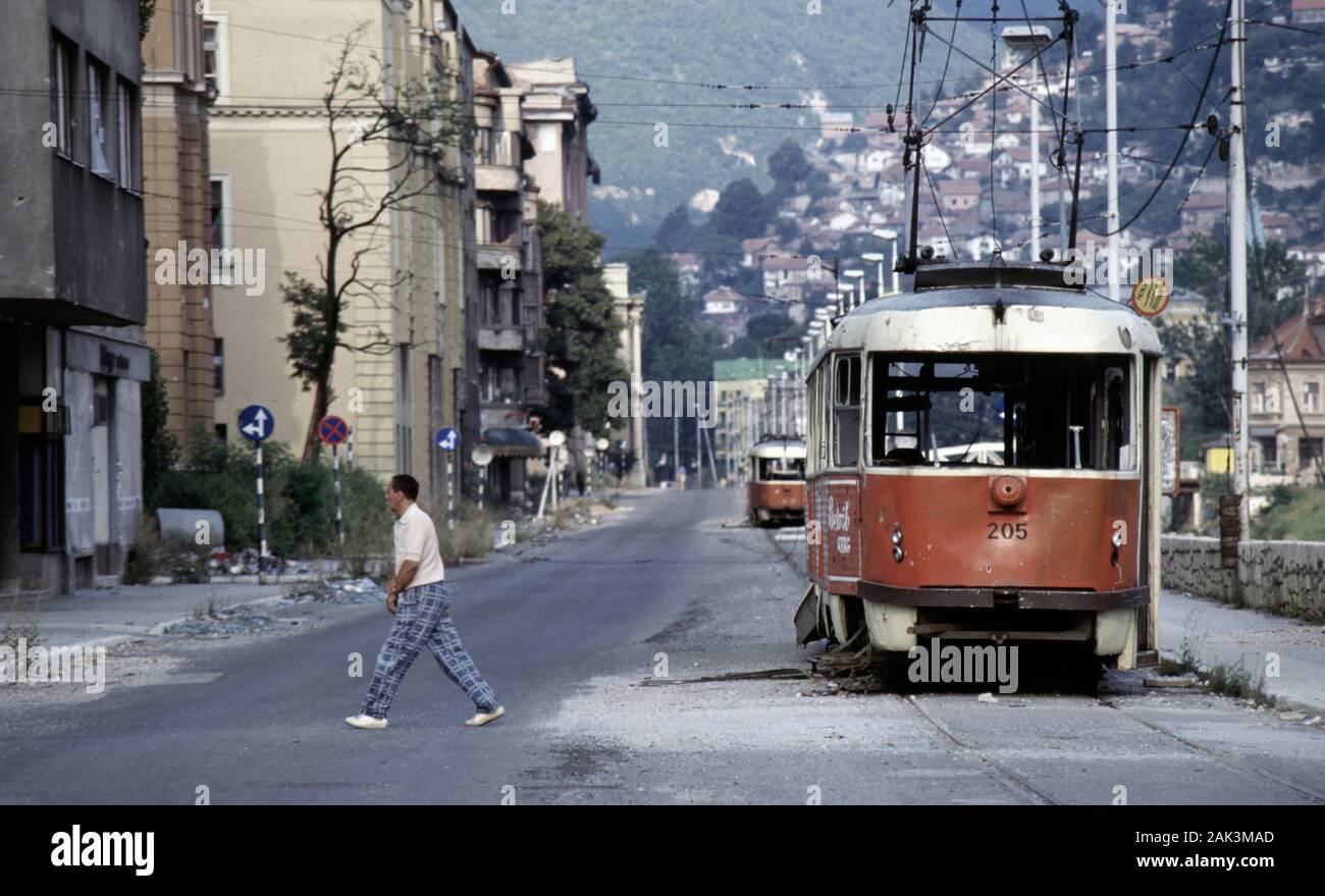 17. August 1993 während der Belagerung von Sarajevo: Der Blick nach Osten entlang Obala Kulina Bana im Stadtzentrum: ruinierte Straßenbahnen stehen entlang einer fast verlassenen Straße aufgegeben. Stockfoto